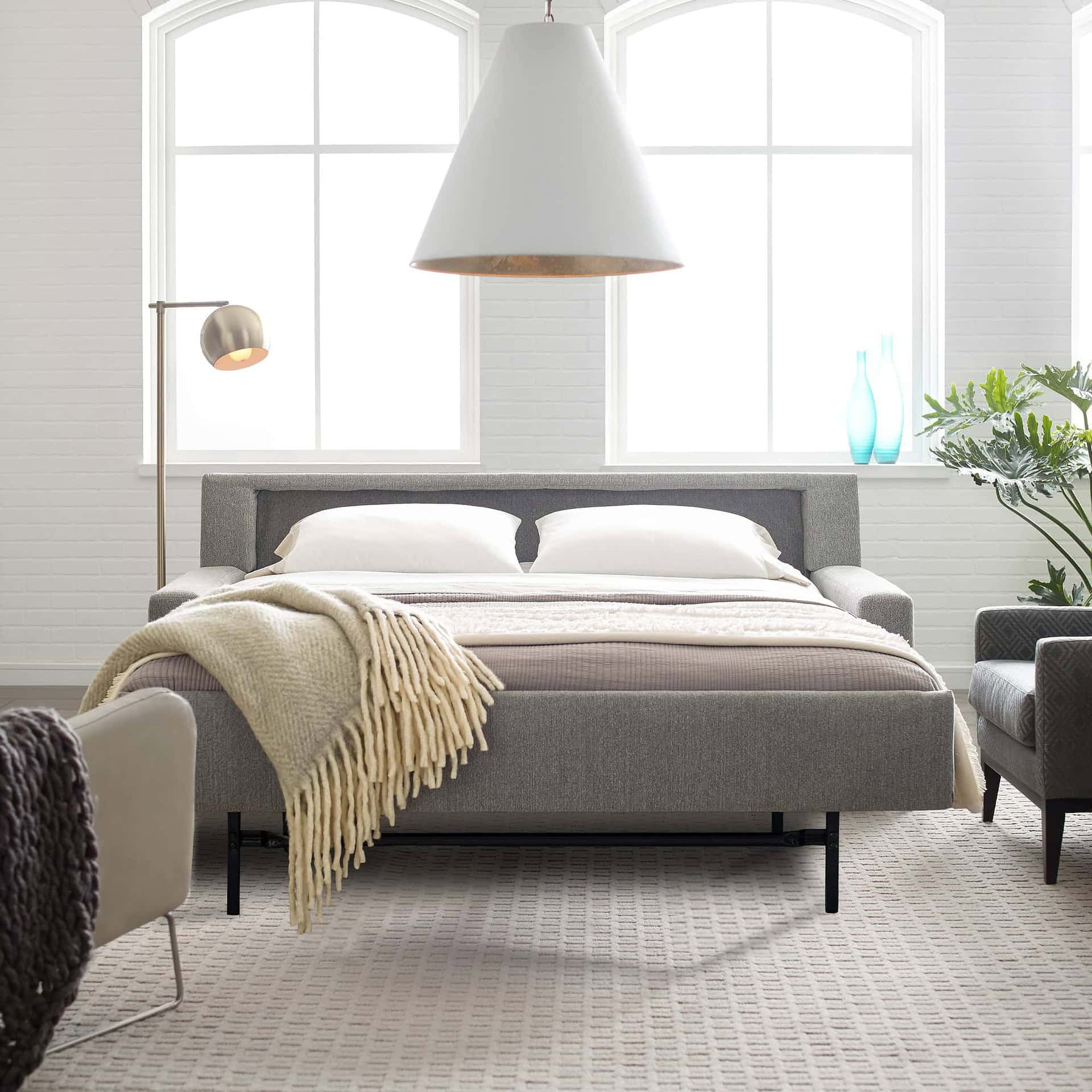 Bright bedroom with contemporary furniture, large windows, and decorative accents, showcasing Sklar Furnishings' stylish designs.