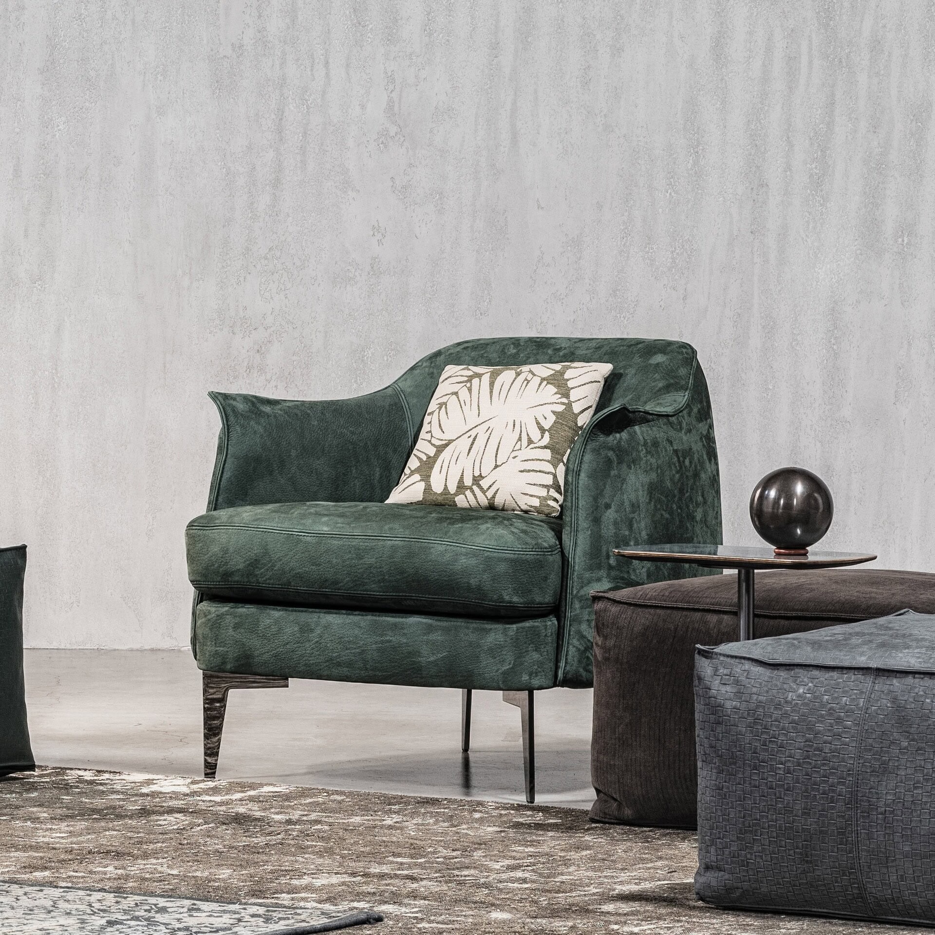 Bohème Upholstered Lounge Armchair in rich green fabric, accented with a patterned throw pillow, positioned near a dark side table in a contemporary setting.