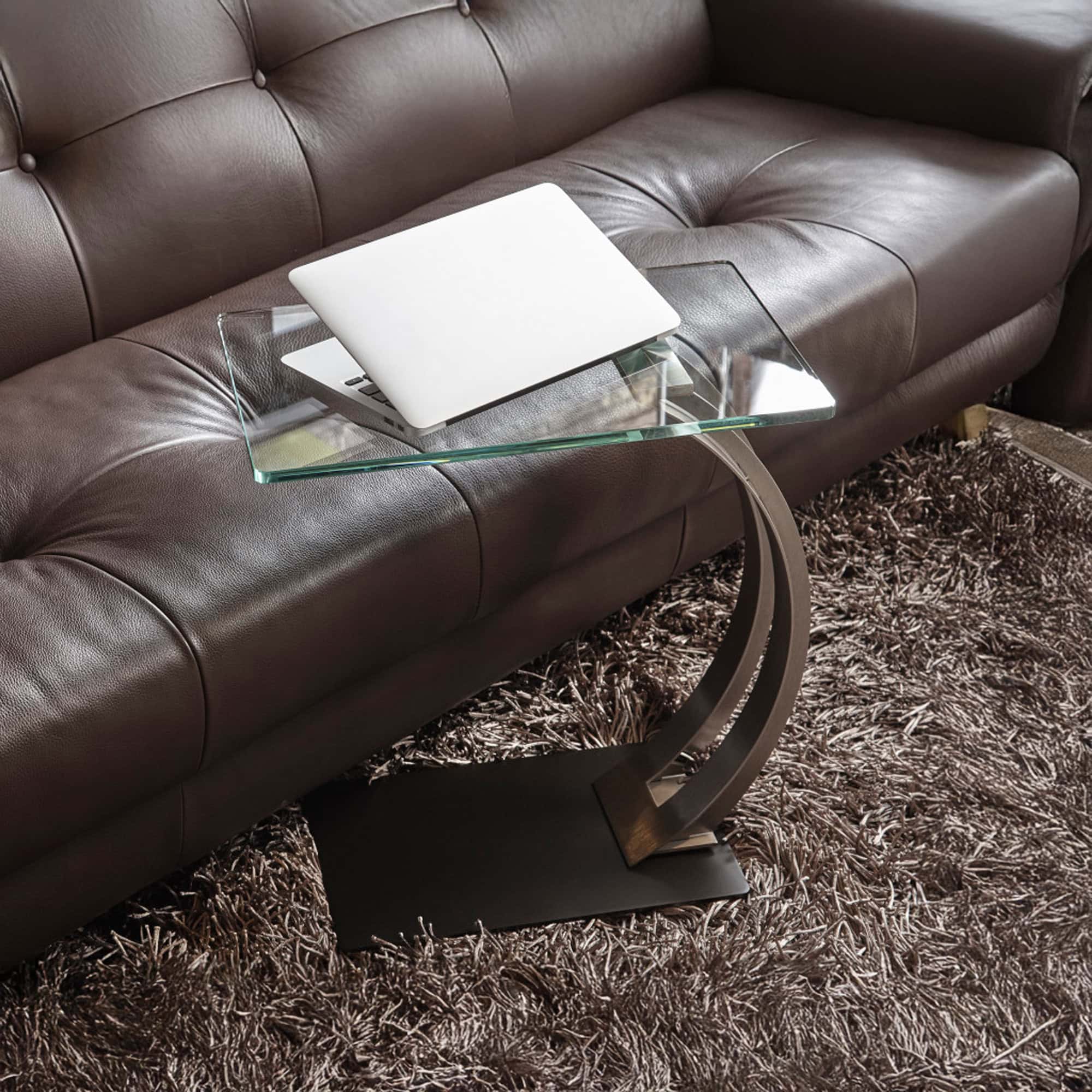 Encore Accent Table styled beside a sofa with clear glass top and champagne-plated arcs.