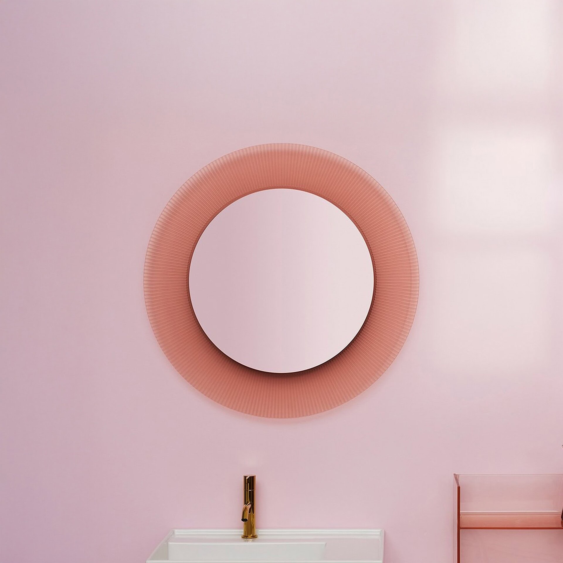 Kartell All Saints round mirror with pleated nude frame displayed on a soft pink wall above sink.