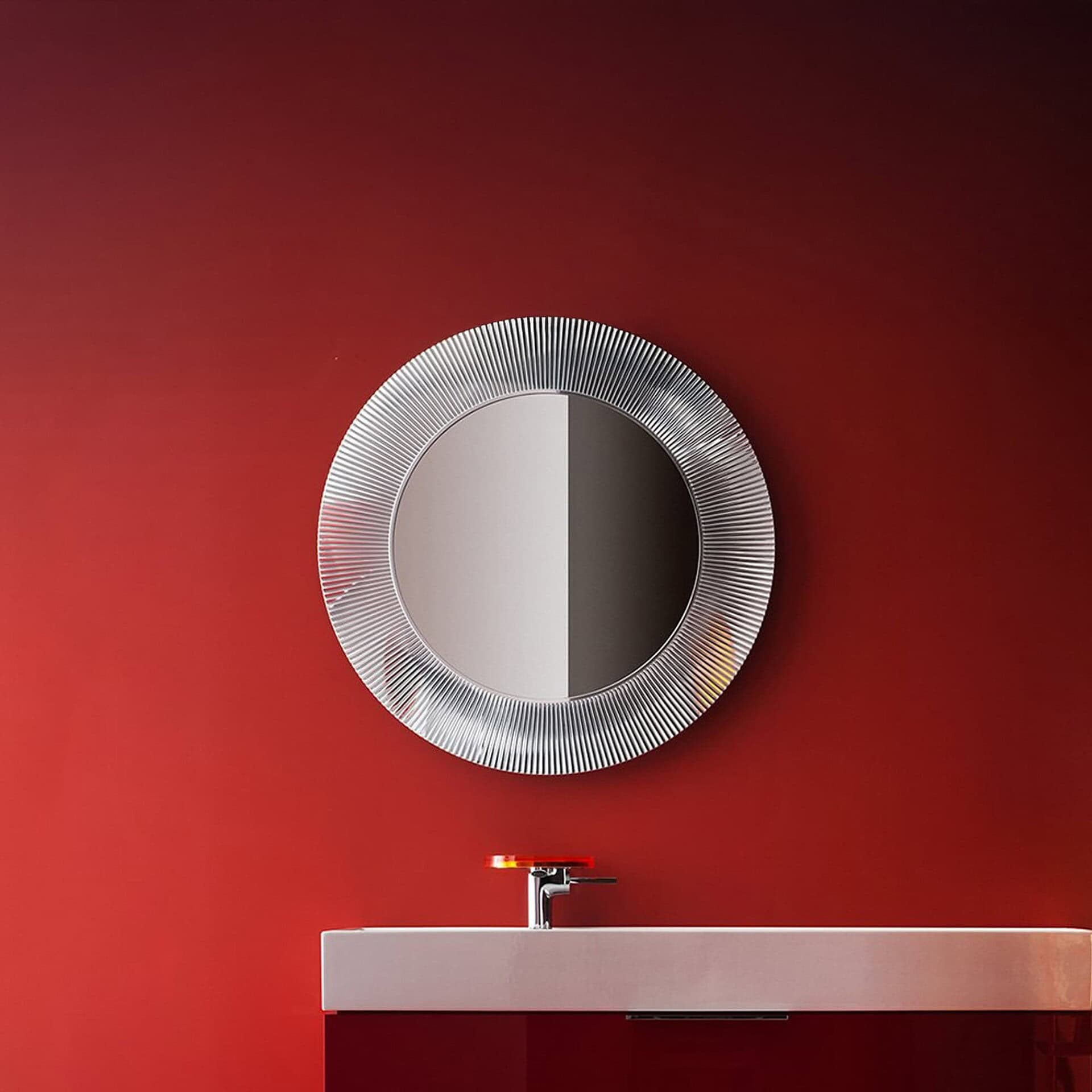 Kartell All Saints metallizzato chrome mirror with pleated frame styled against a deep red wall.
