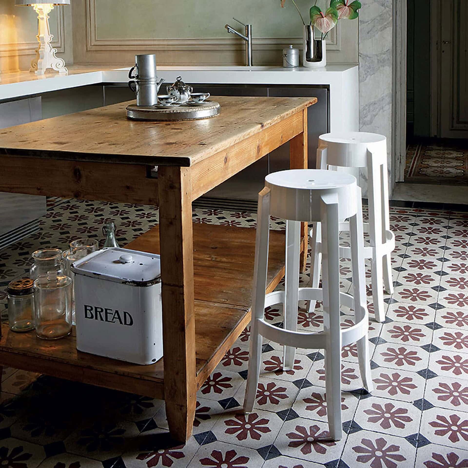 Crystal Charles Ghost stools at a kitchen counter with patterned tile flooring.
