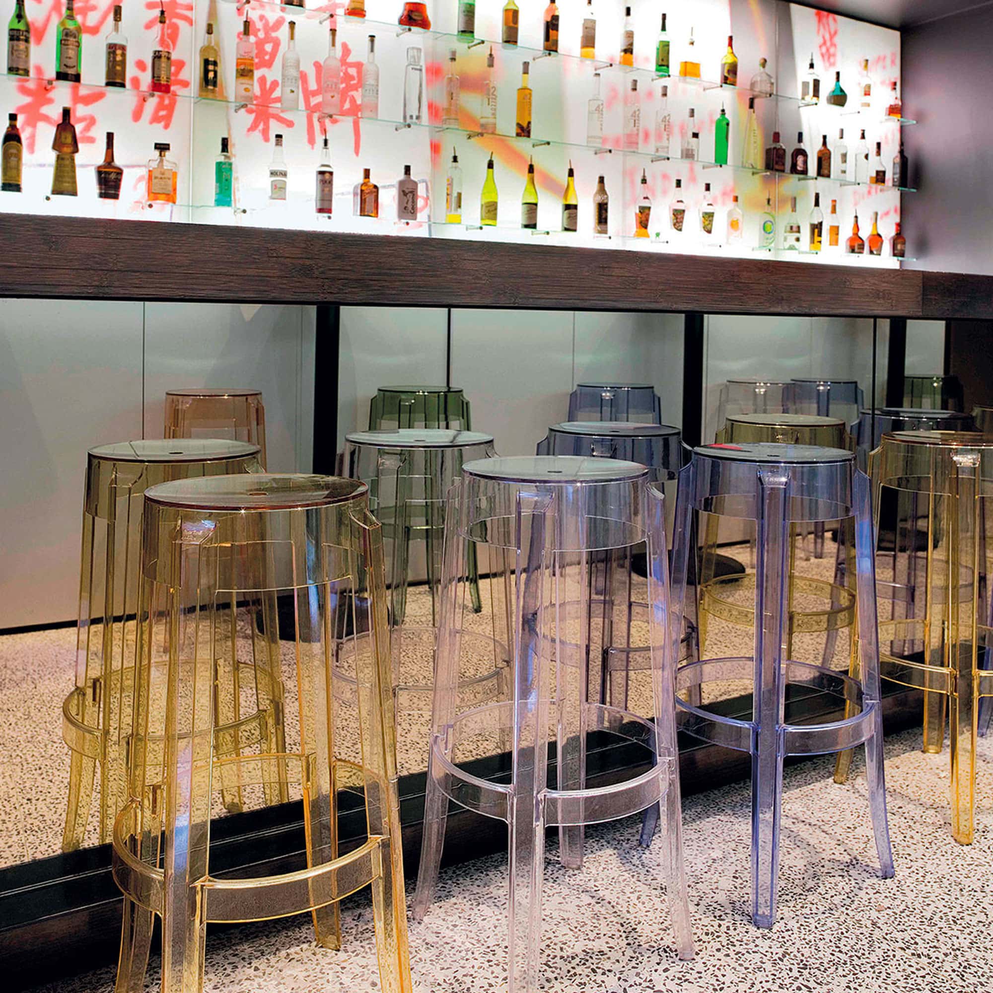 Amber Charles Ghost stools lined up along a bar in a contemporary restaurant.