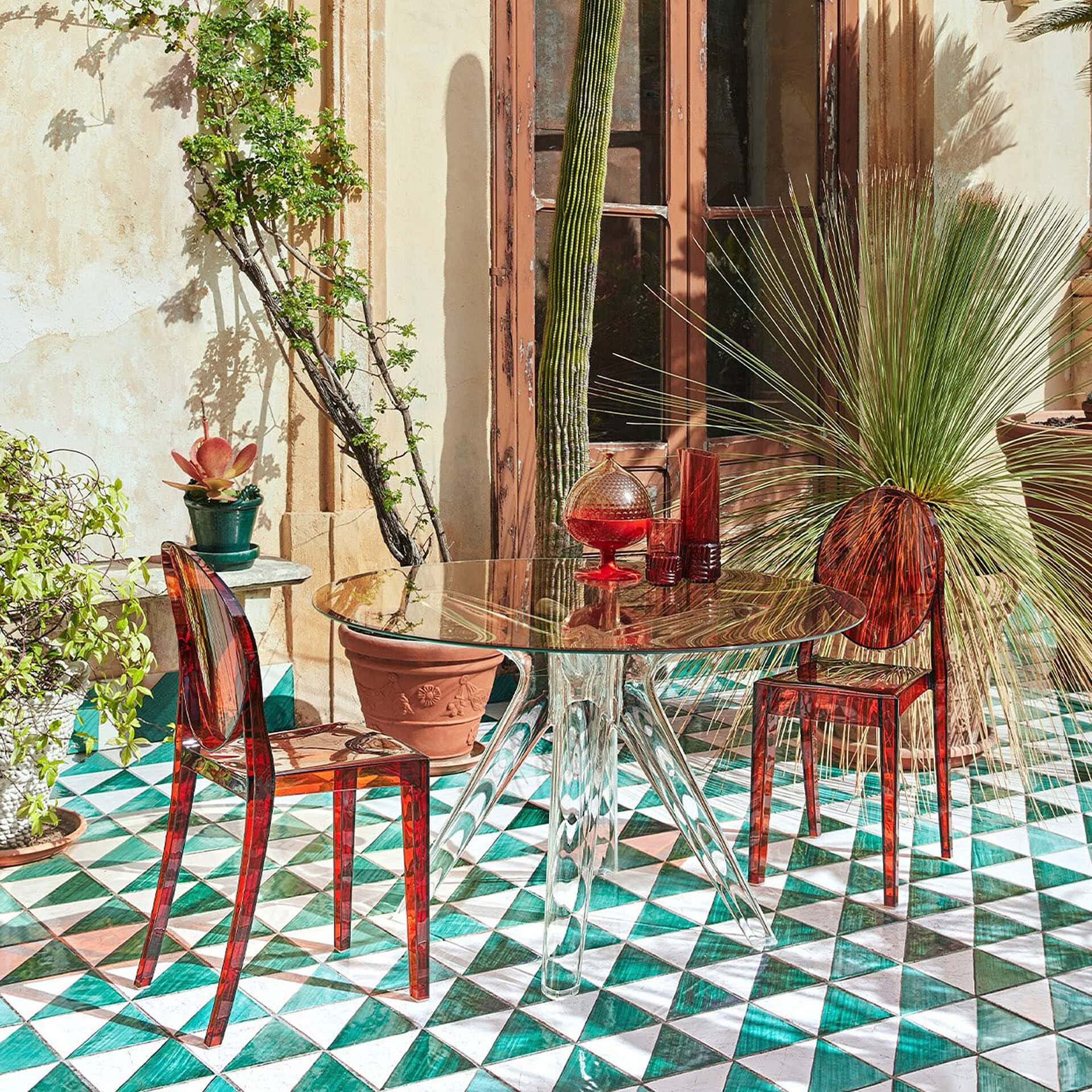 Outdoor dining table with colorful chairs and decorative plants.