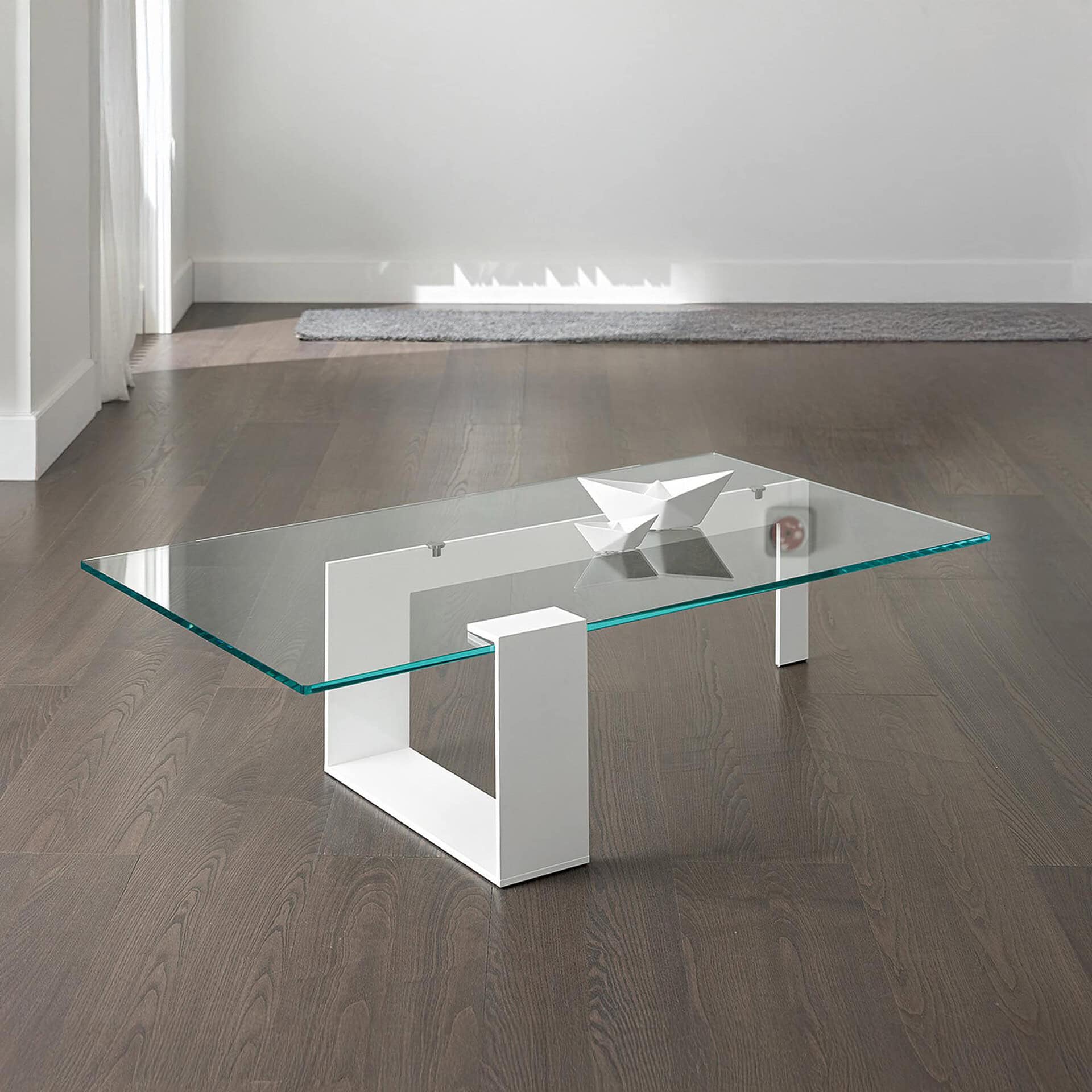 Plinsky Glass Low Coffee Table with clear glass top and white lacquered metal base in a minimalist interior.