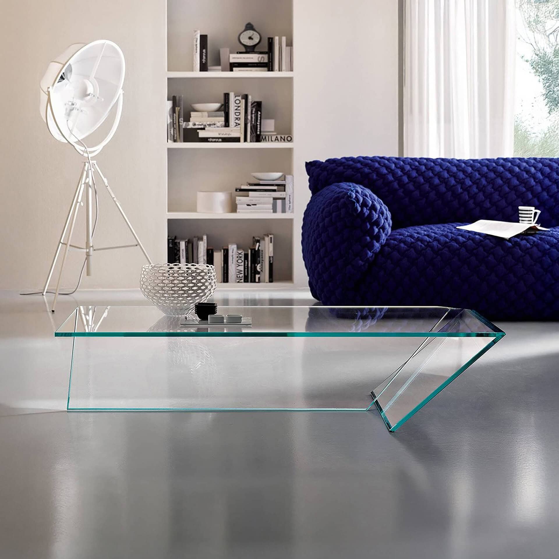 Modern living room featuring a plush, deep blue sofa and a sleek glass coffee table in a bright, con.