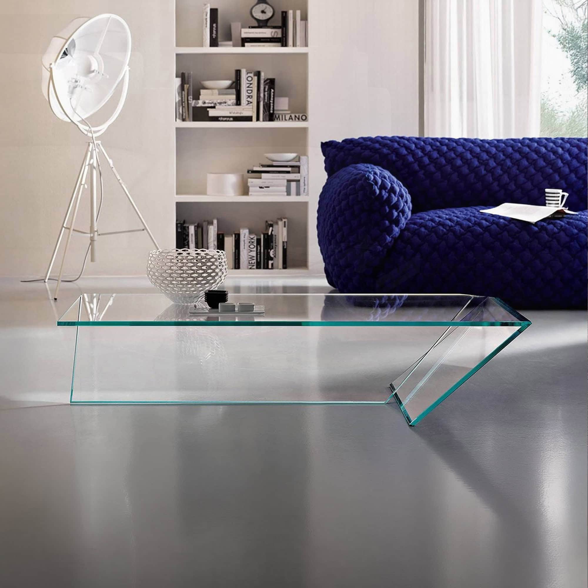 Modern living room featuring a plush, deep blue sofa and a sleek glass coffee table in a bright, con.