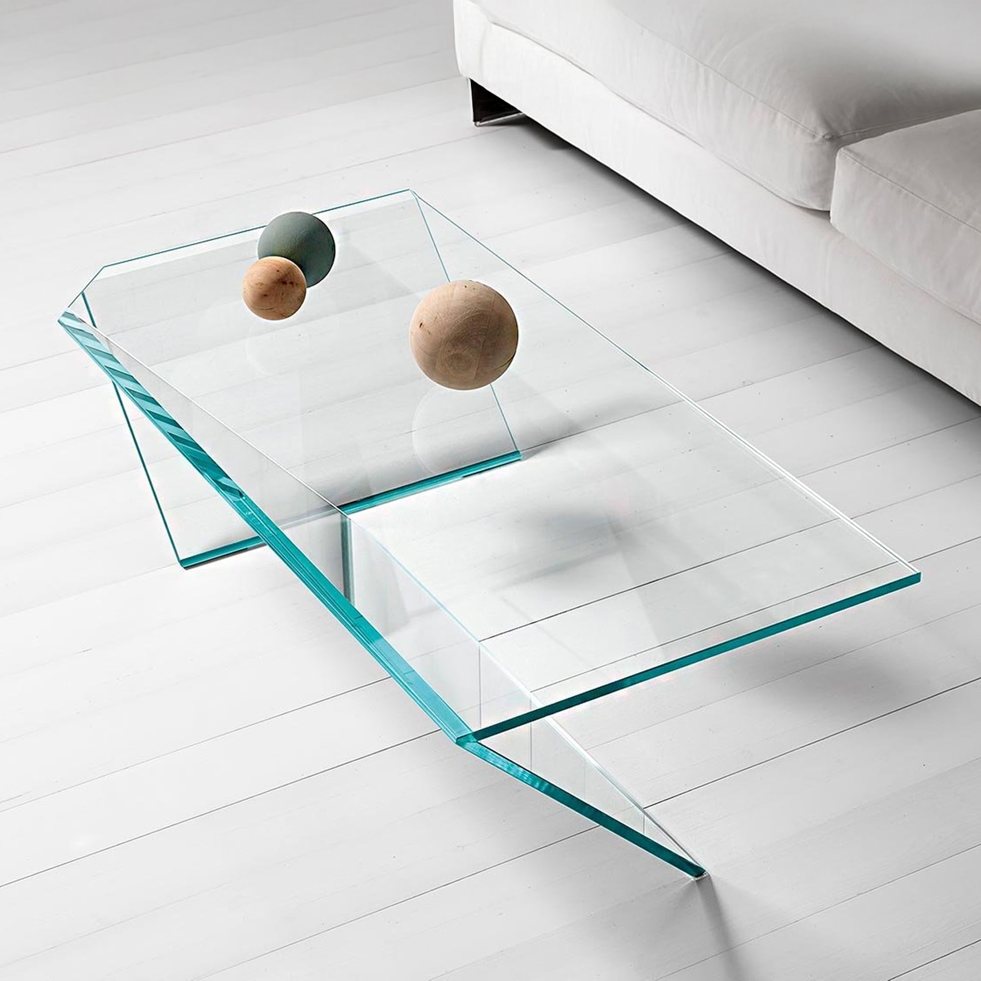 Ti Low Table in clear glass placed in a light modern space, styled with decorative spheres on top.