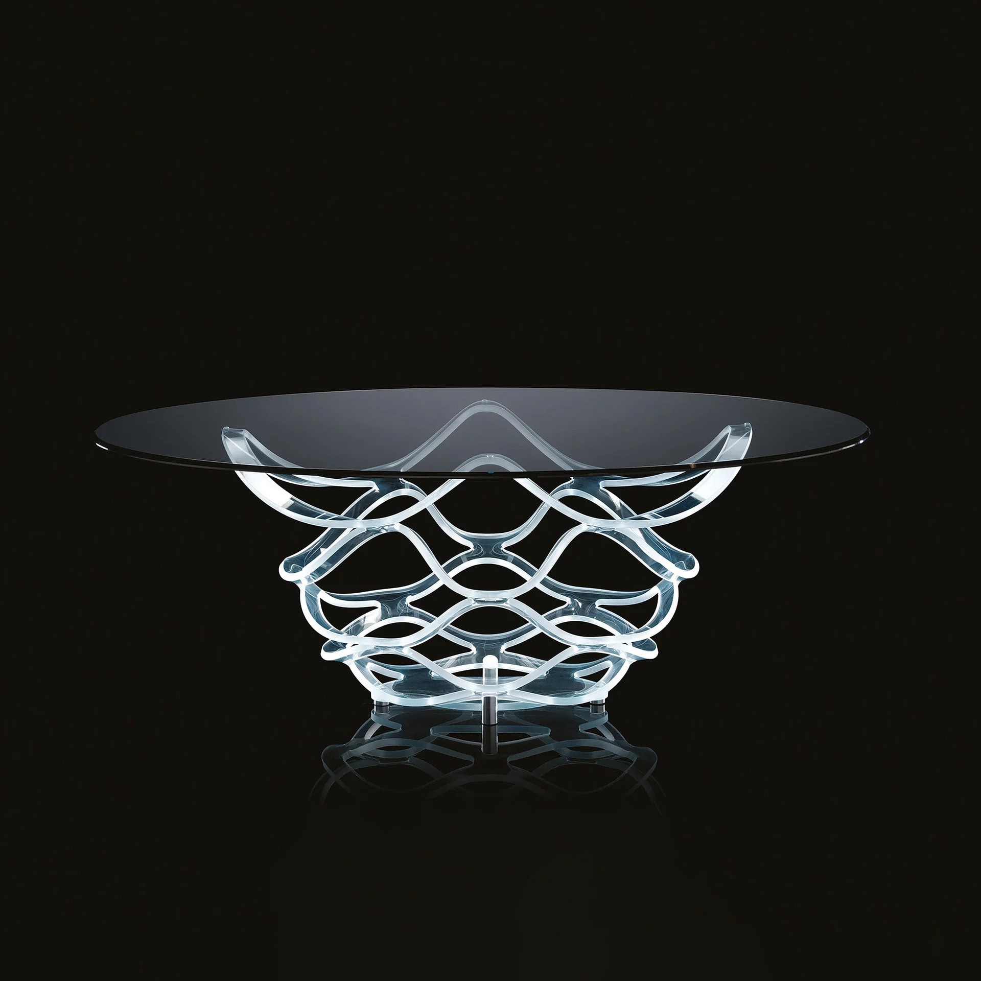 A modern coffee table with a round clear glass top and an intricate, sculptural base made of translucent, wavy, interlocking bands, set against a black background.