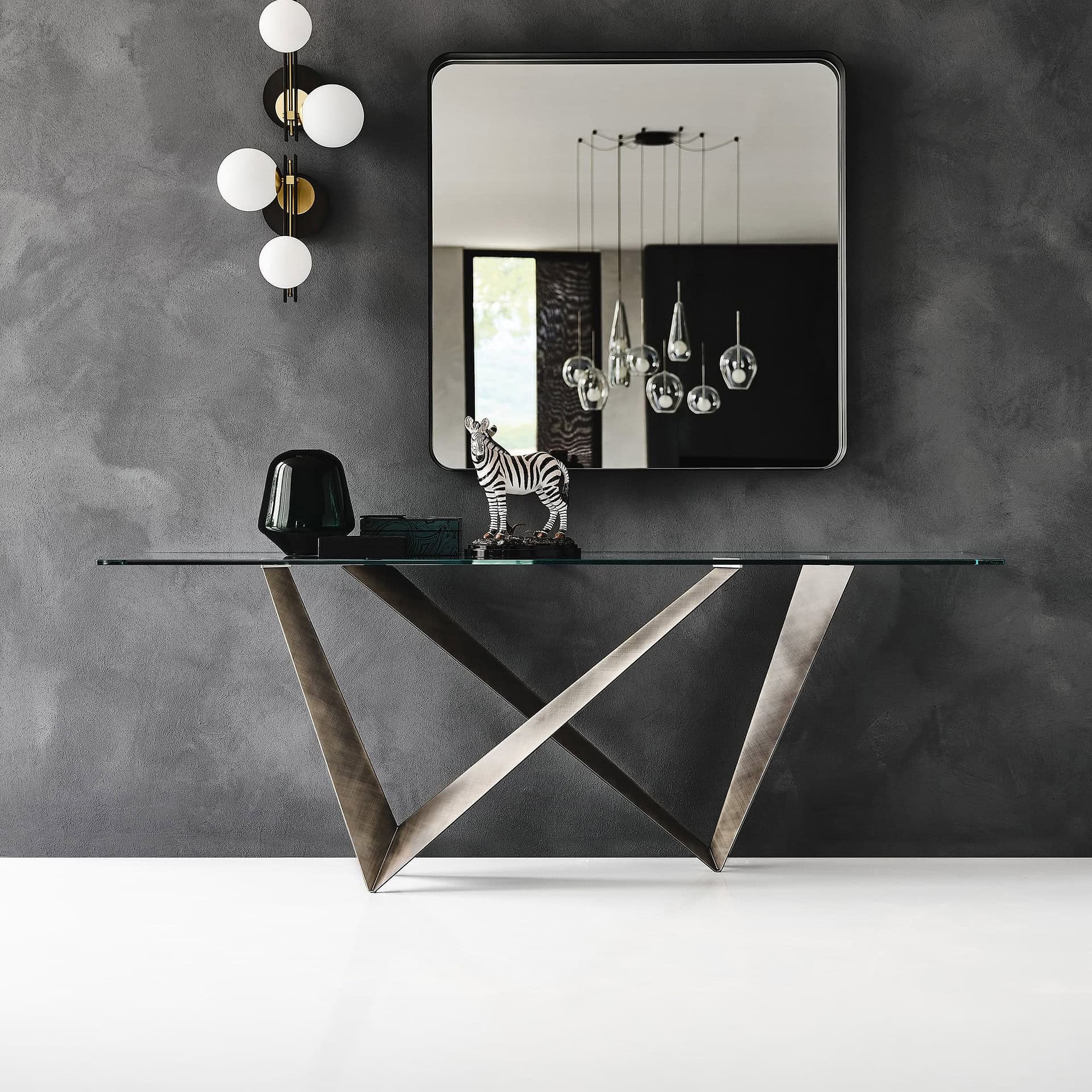 Sleek Westin sculptural console table with glass top and modern geometric metal base. Perfect for co.