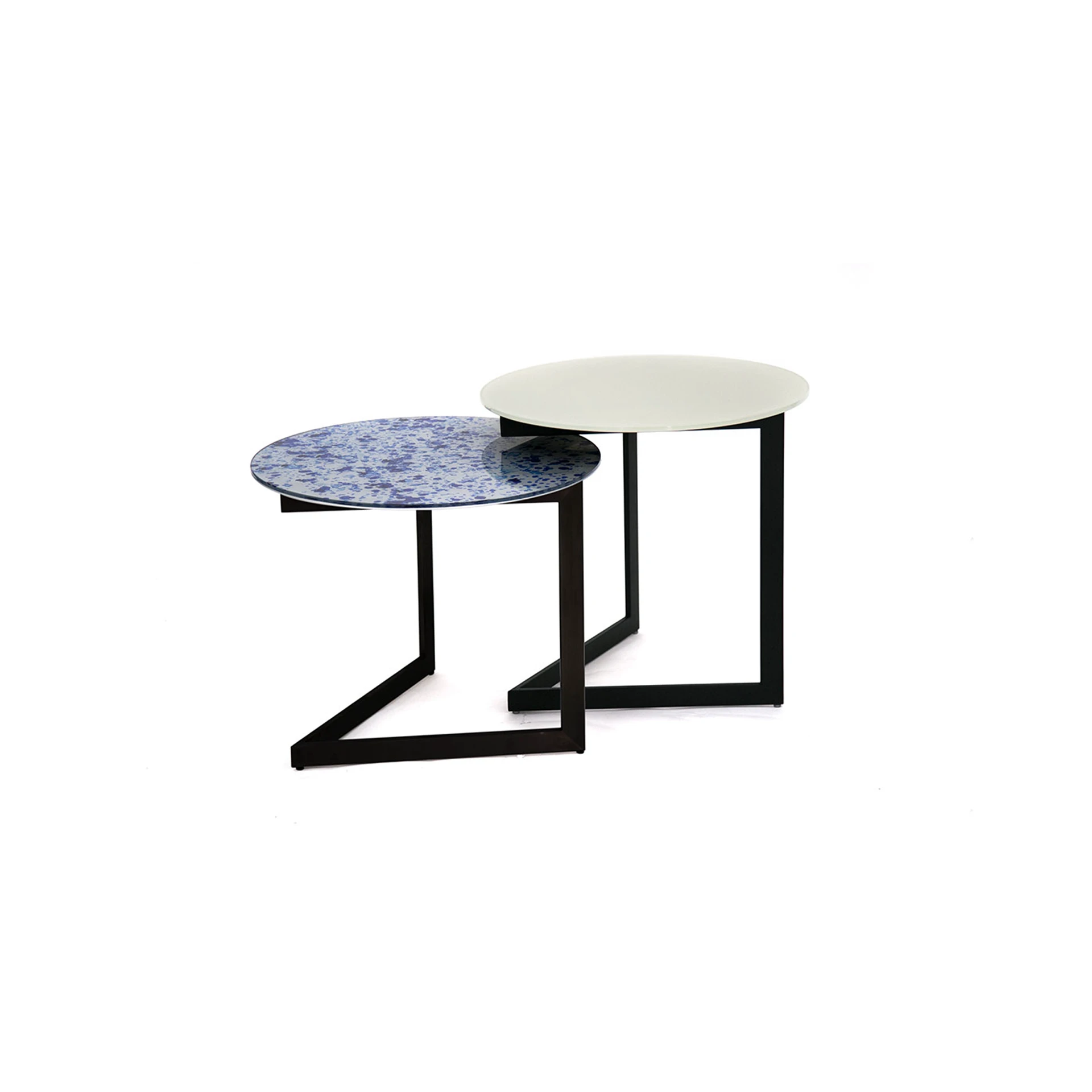 Two nesting tables with round glass tops and black metal bases. One top is blue and white patterned, the other is solid cream.
