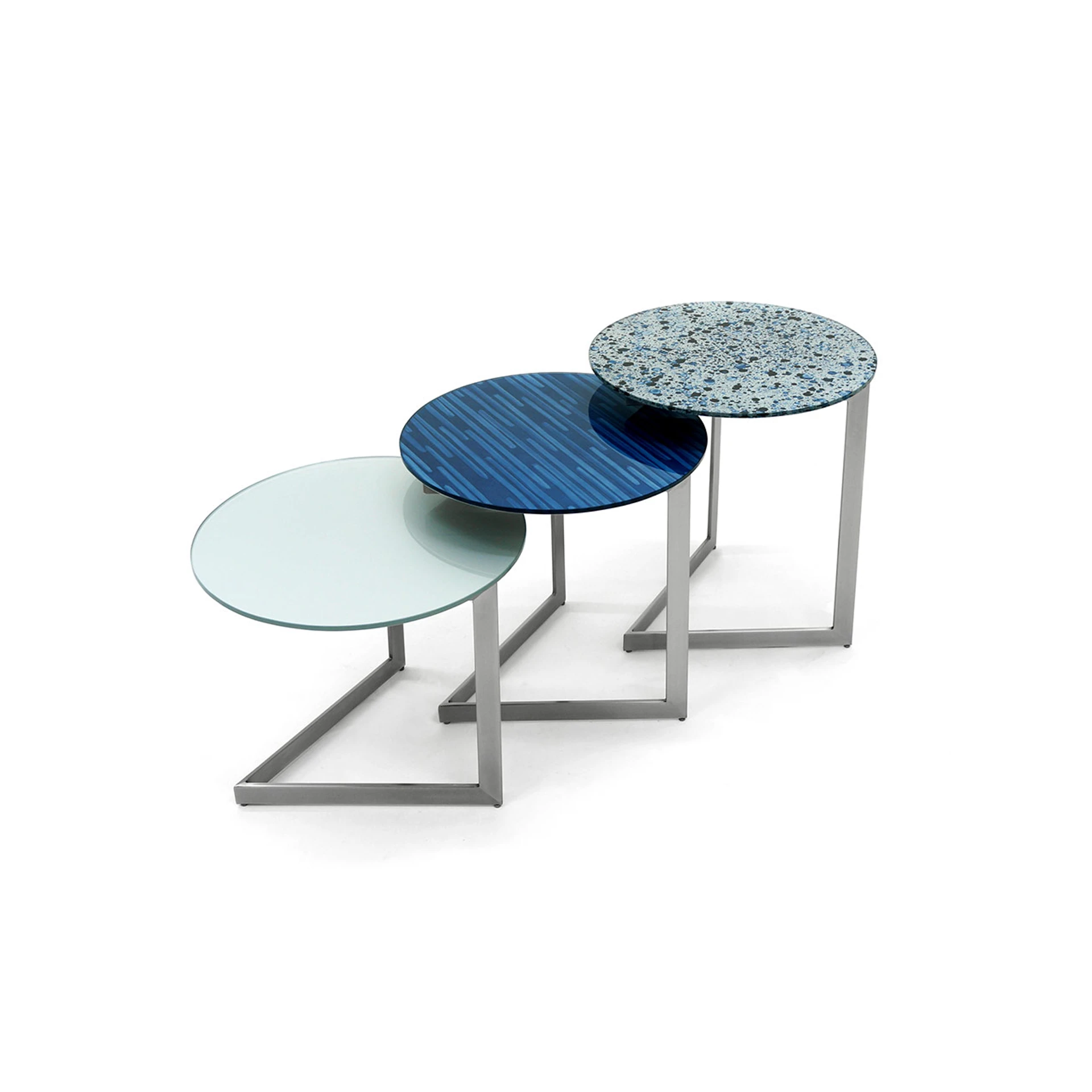 Three round nesting tables with metal bases. From left to right, the glass tops are light blue, dark blue striped, and speckled blue.