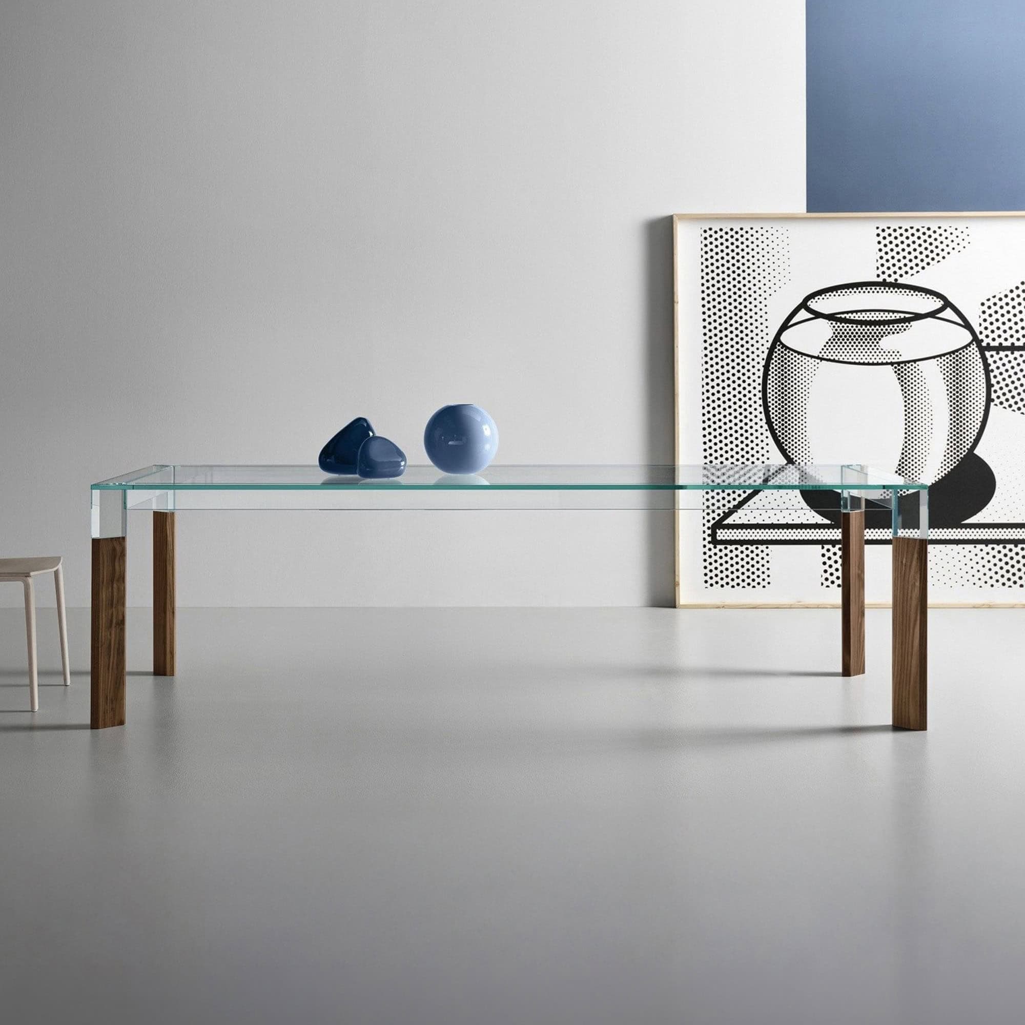 Modern glass dining table with wooden legs in minimalist interior.