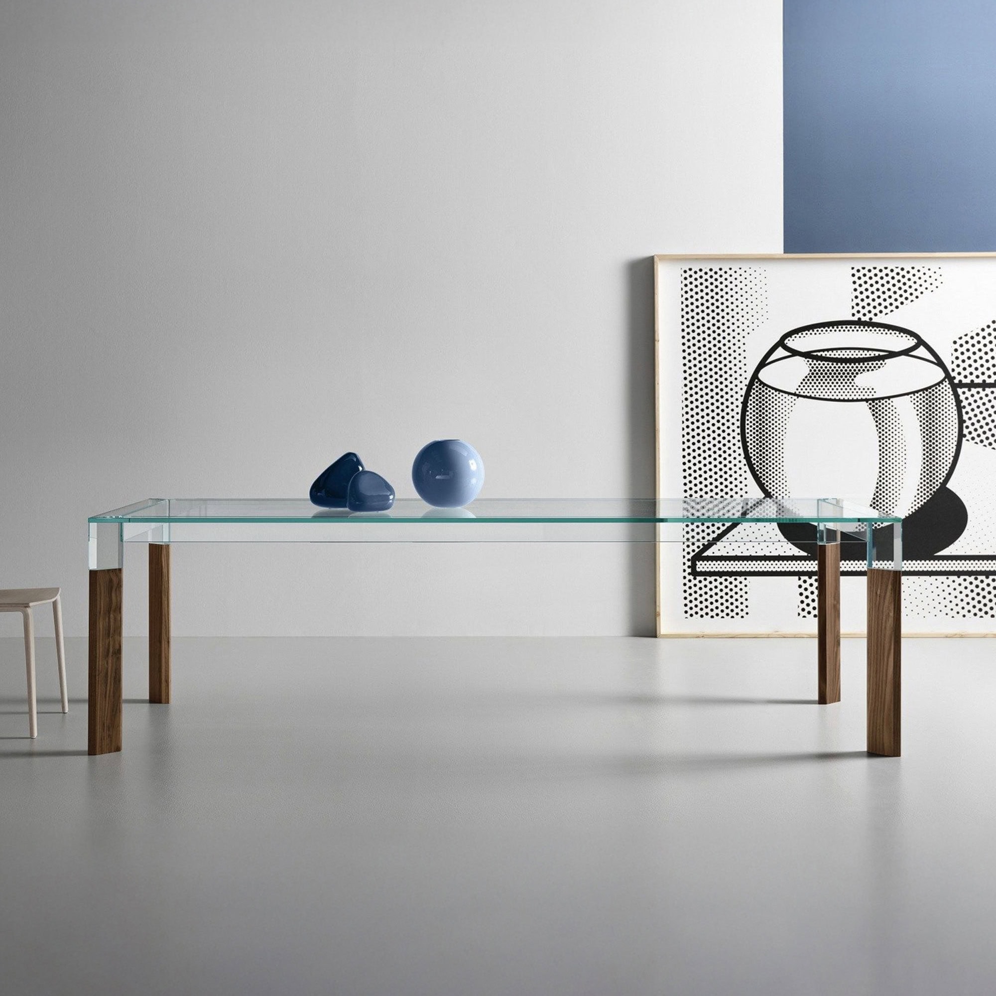 Perseo Extra-Clear Glass Dining Table with natural wood legs styled in a minimalist dining room
