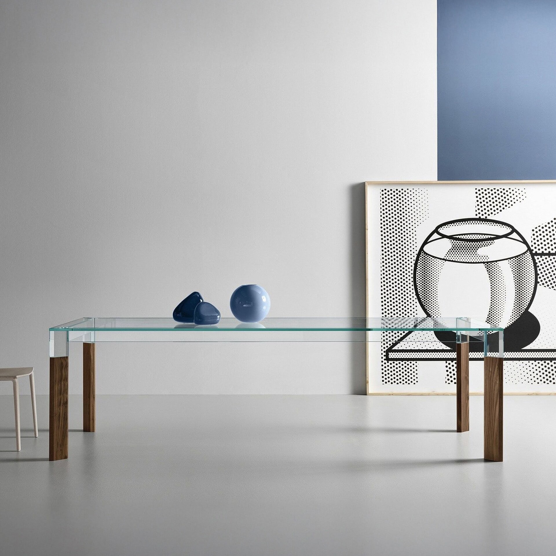 Perseo Extra-Clear Glass Dining Table with natural wood legs styled in a minimalist dining room