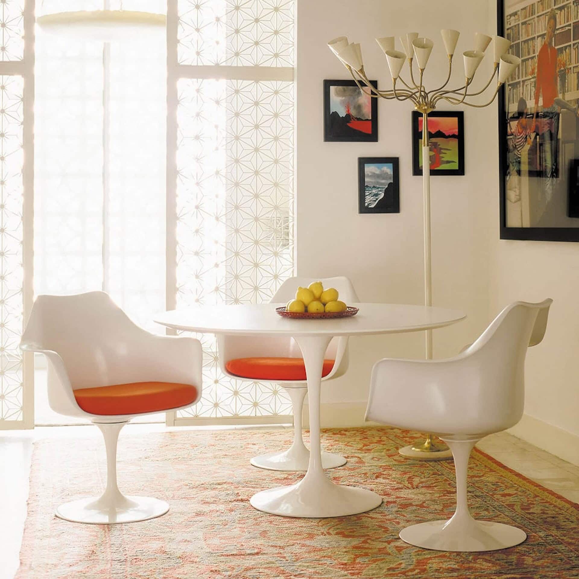 a white table with orange chairs and a chandelier