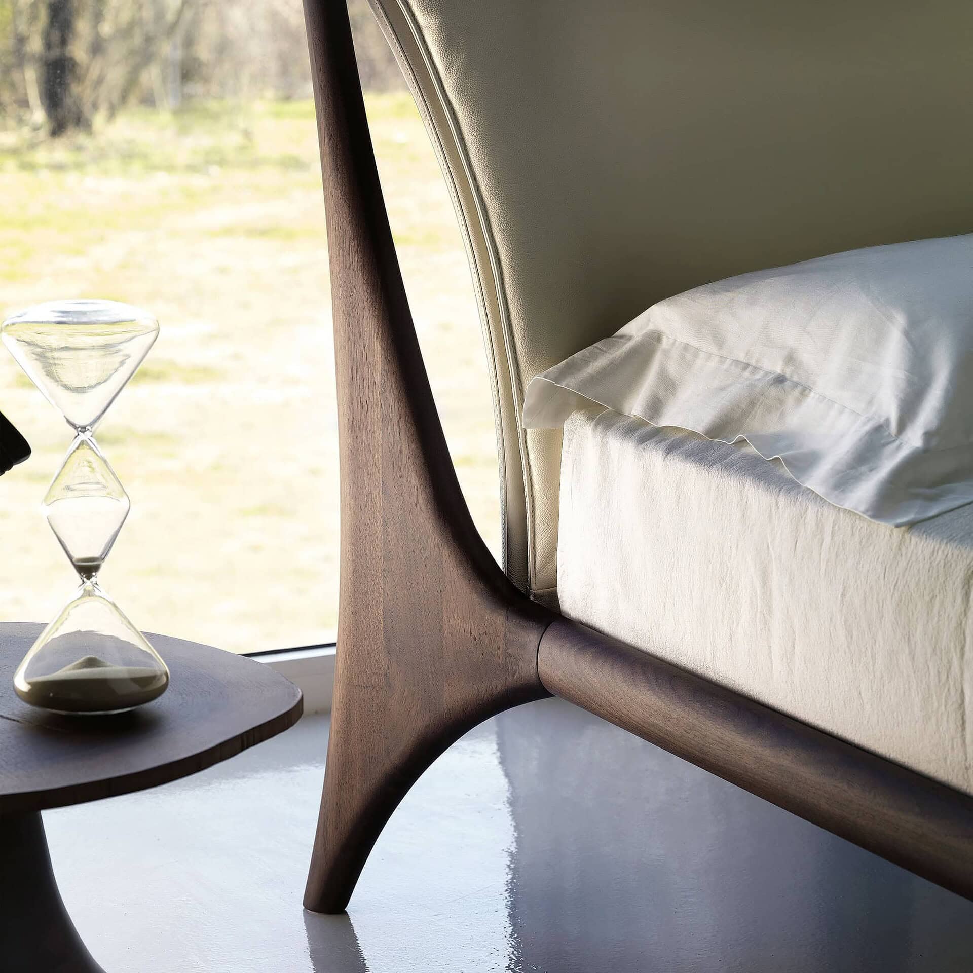 Close-up of Nelson Wood Frame Upholstered Bed leg detail in sculpted walnut wood.