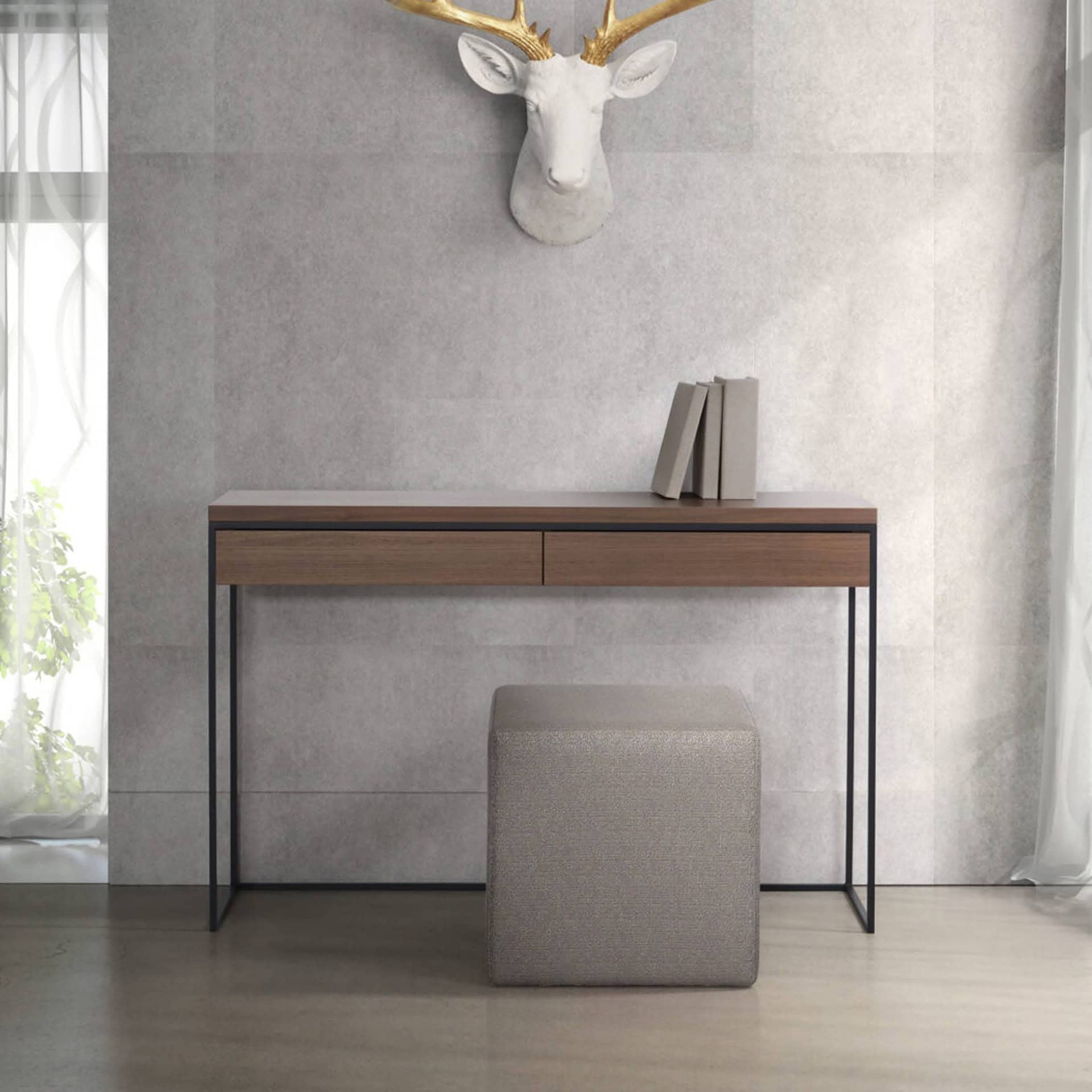 Beige upholstered ottoman placed neatly beneath a slim wooden desk with black metal legs.