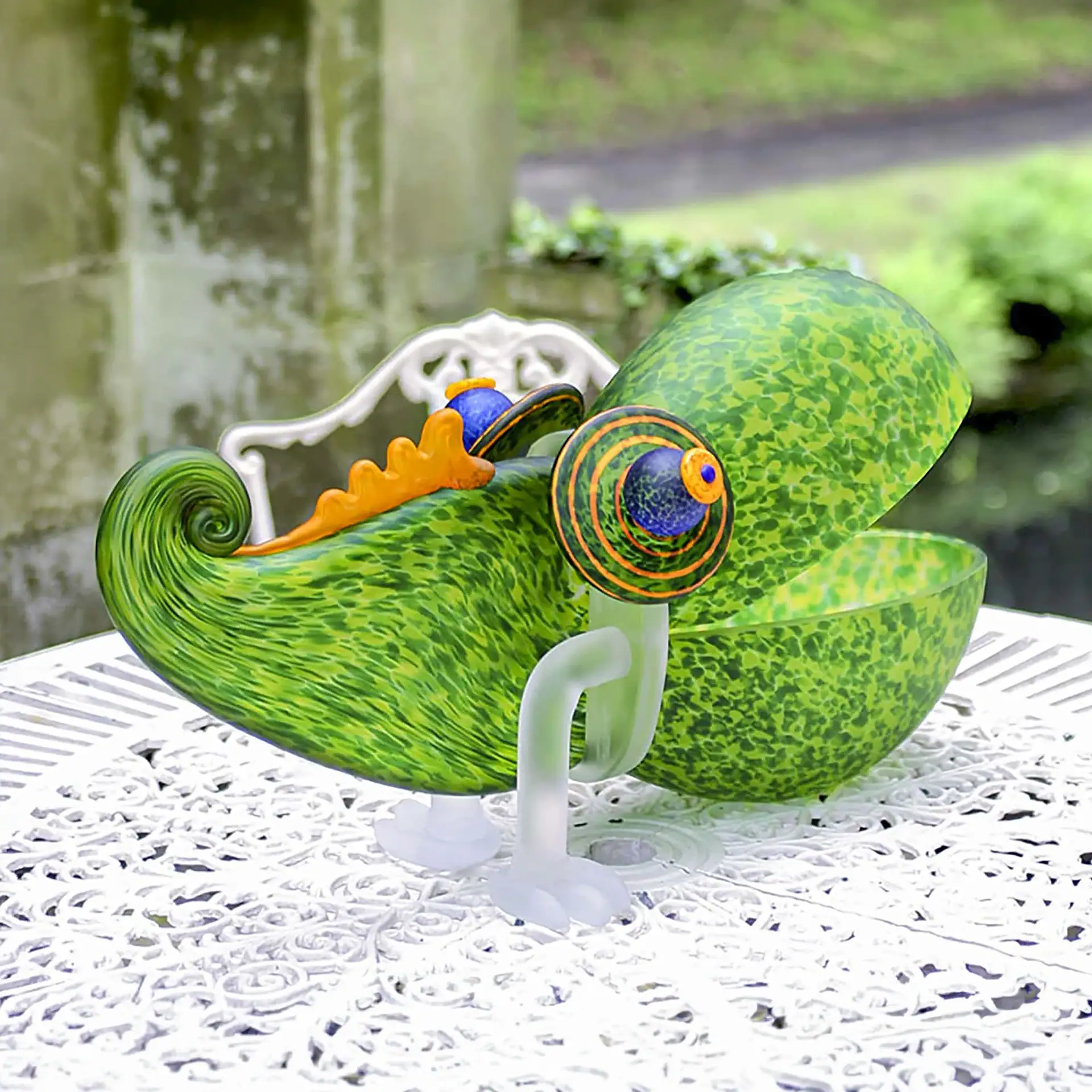 Chameleon Big Glass Bowl with large eyes and an open back, sitting on a white ornate table outdoors.