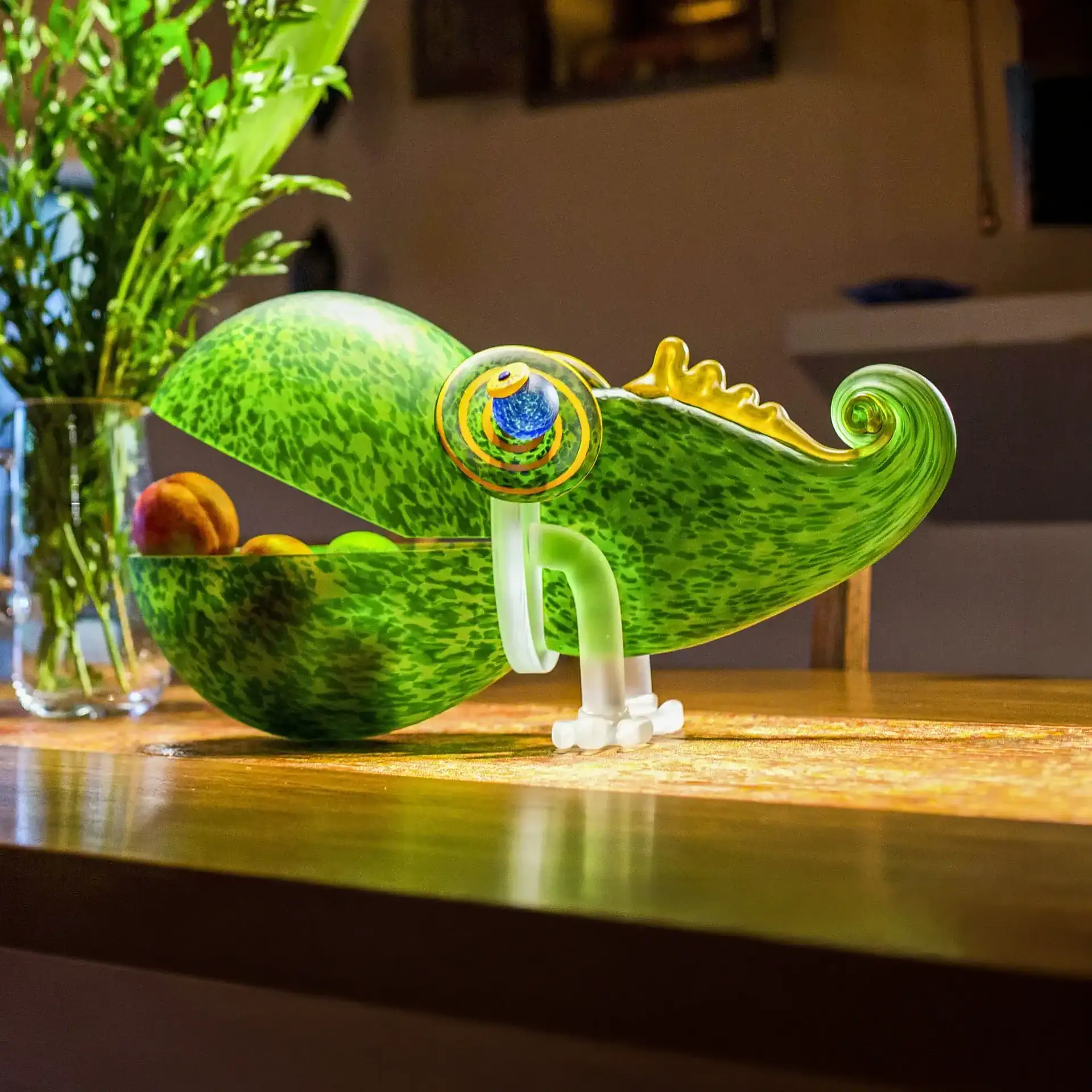 Chameleon Big Glass Bowl with an open lid, holding fruit, sits on a wooden table.