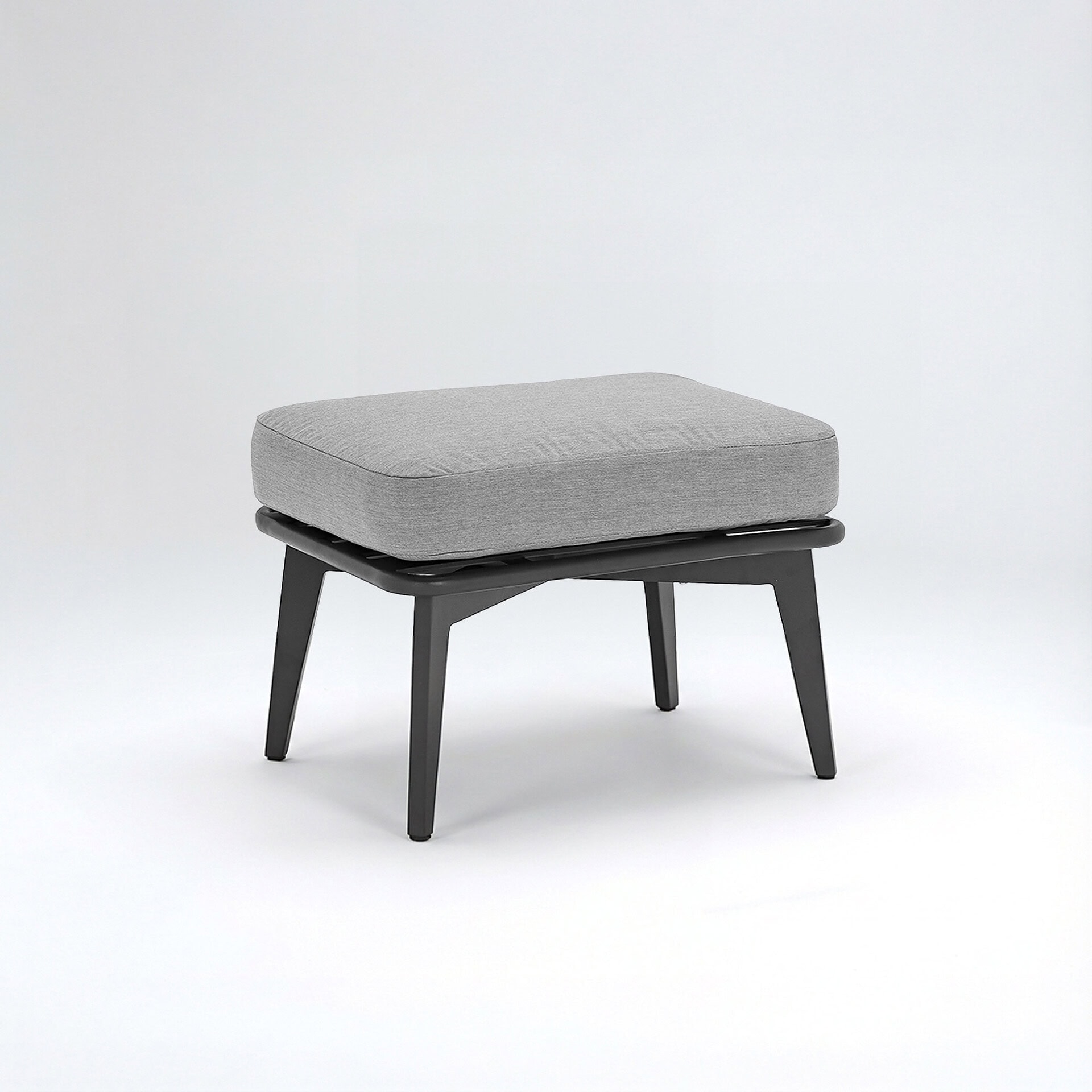 A modern, rectangular ottoman with a light grey fabric cushion and dark grey tapered legs, set against a white background.