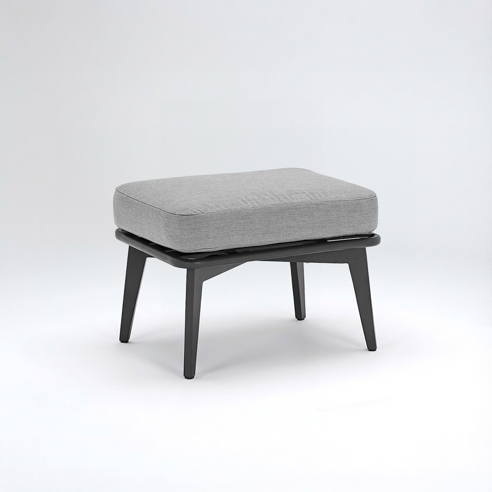 A modern, rectangular ottoman with a light grey fabric cushion and dark grey tapered legs, set against a white background.