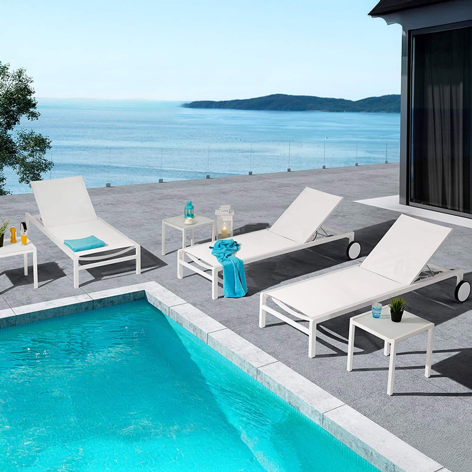 Ella Chaise Lounges in white set beside an infinity pool with a panoramic water view.