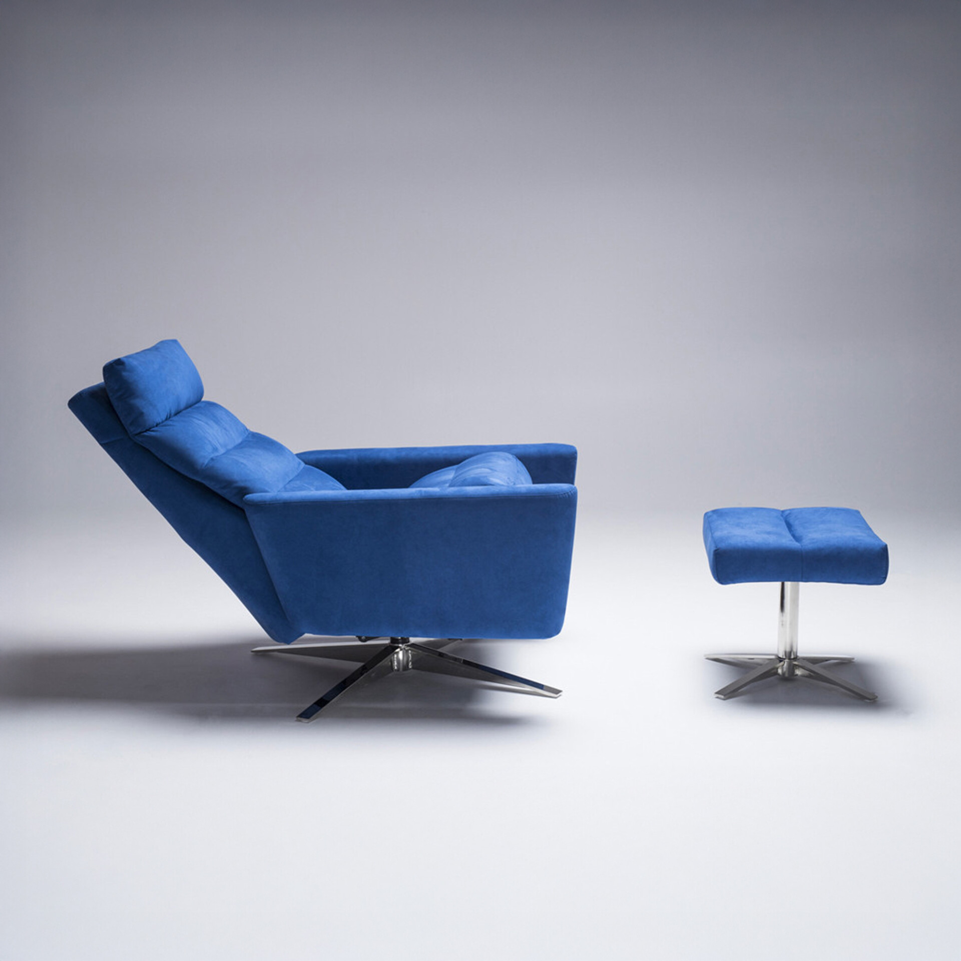 A vibrant blue upholstered recliner chair and matching ottoman on a light gray background. Both pieces feature polished chrome star-shaped bases.