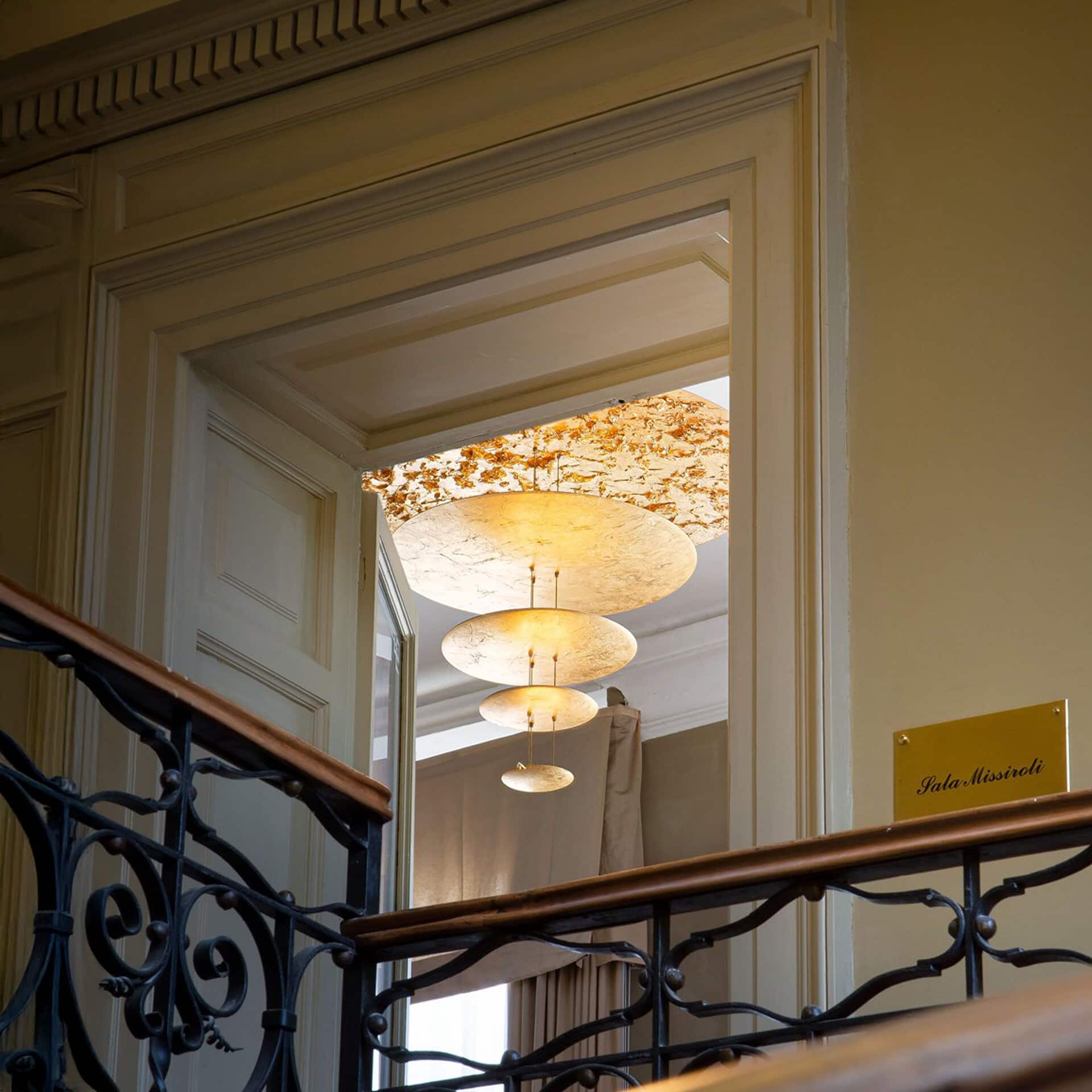 Macchina della Luce Pendant Light hanging above a staircase with golden reflections.