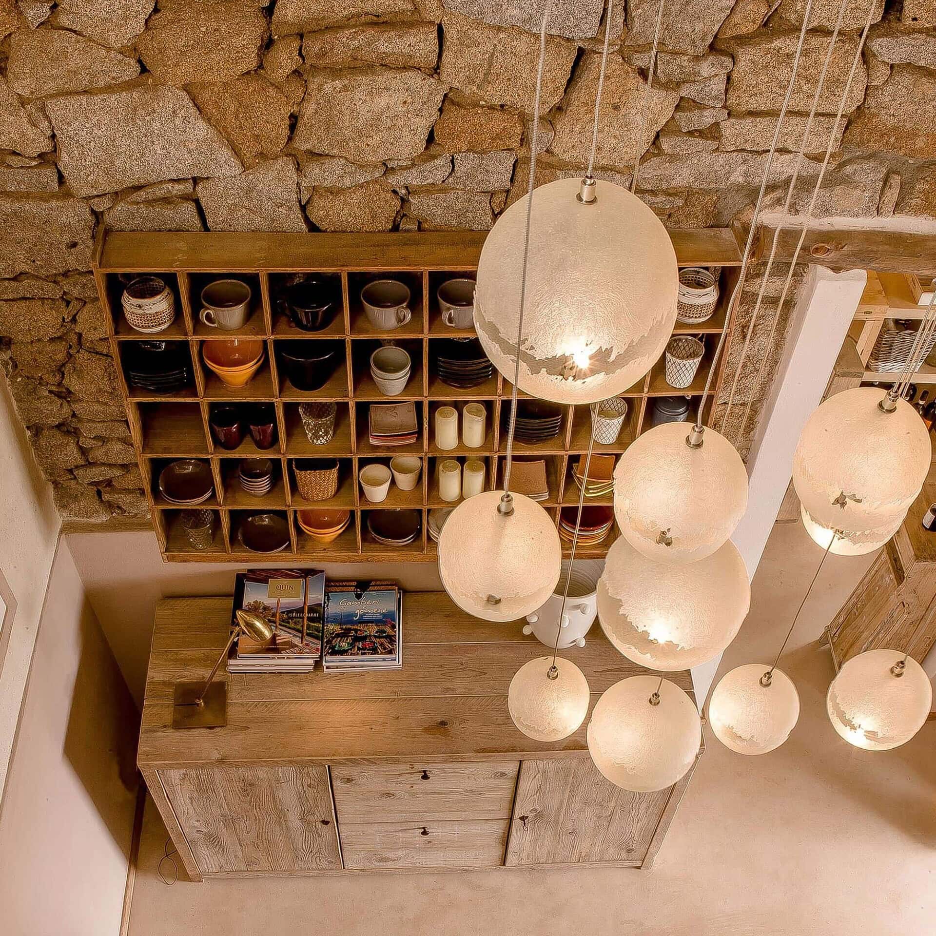 PostKrisi pendant chandelier grouping in a rustic stone interior, demonstrating versatility in different settings.