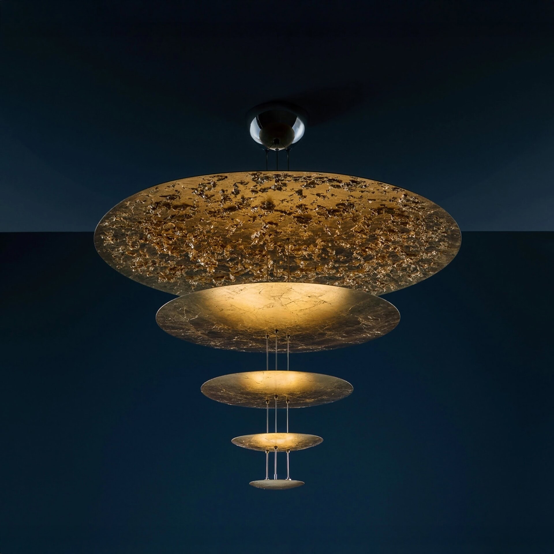 Macchina della Luce Pendant Light with layered gold leaf discs against a dark background.