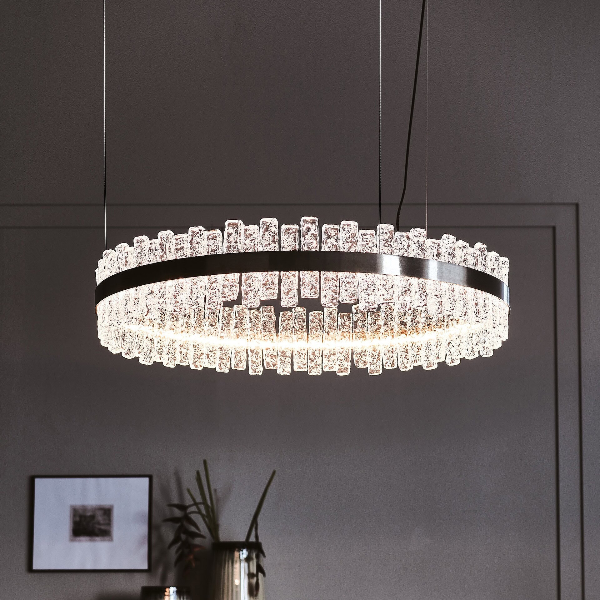 Round Phoenix LED Handmade Glass Chandelier suspended above dining area with minimalist decor.