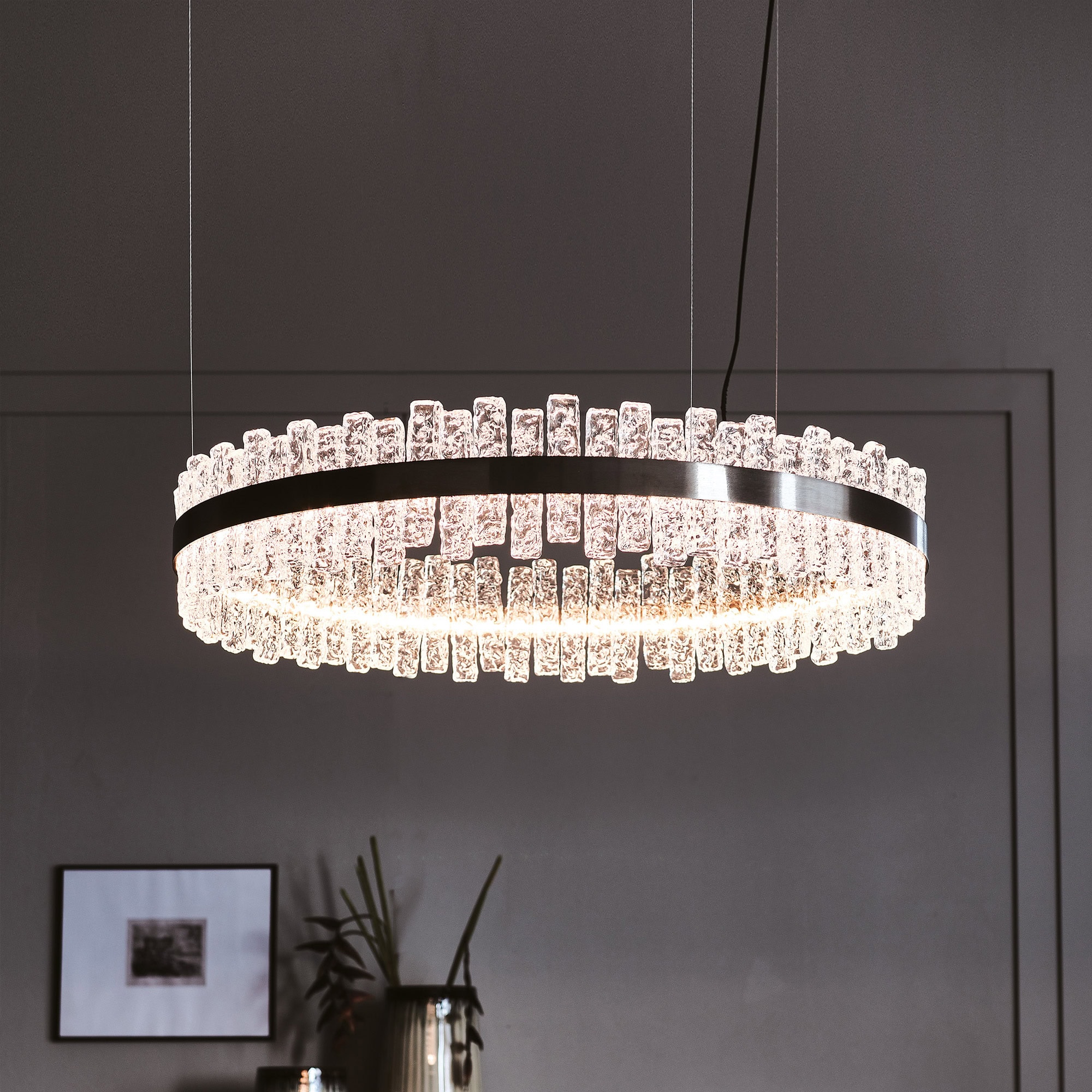 Round Phoenix LED Handmade Glass Chandelier suspended above dining area with minimalist decor.