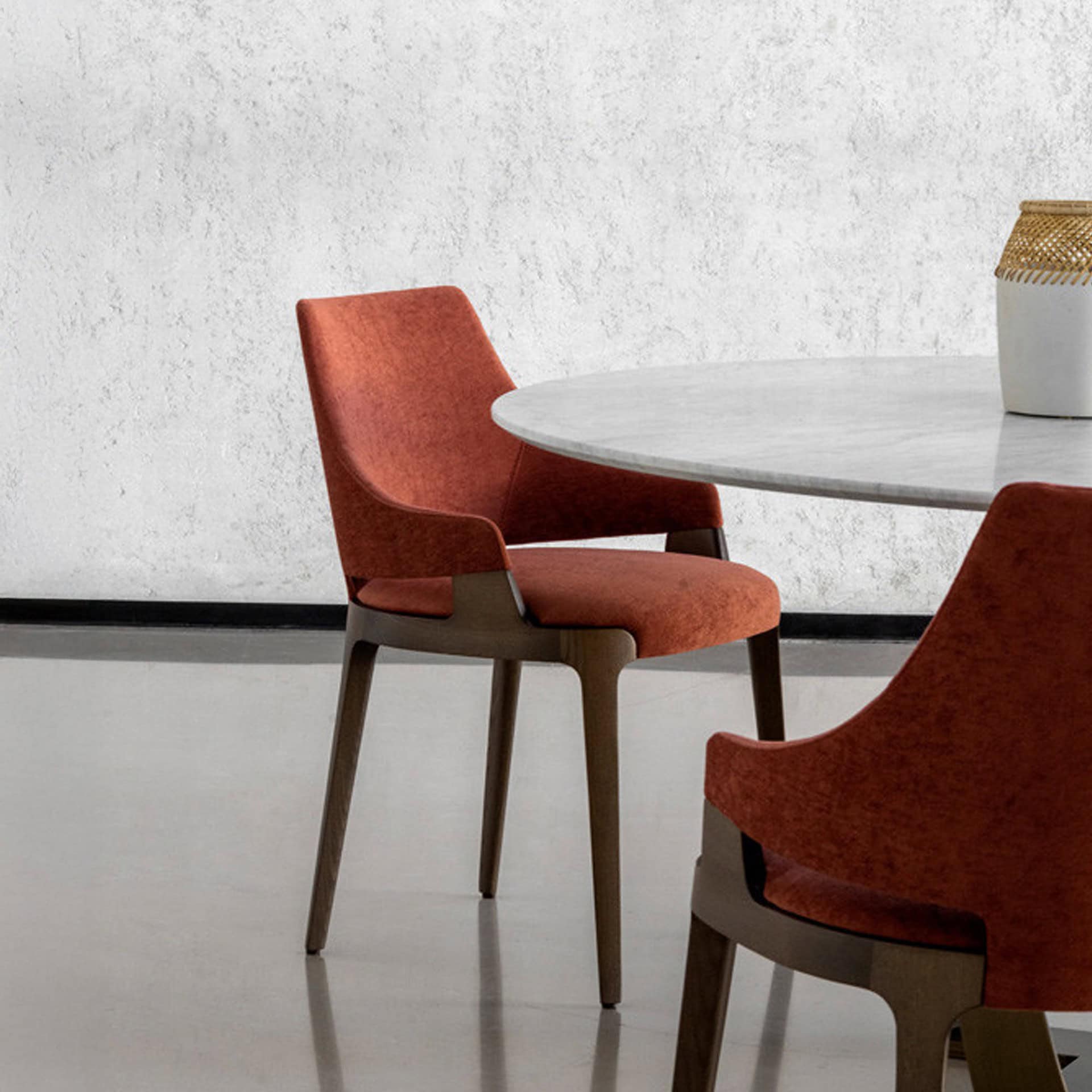 Rear view of two red Velis dining chairs placed beside a modern round table.