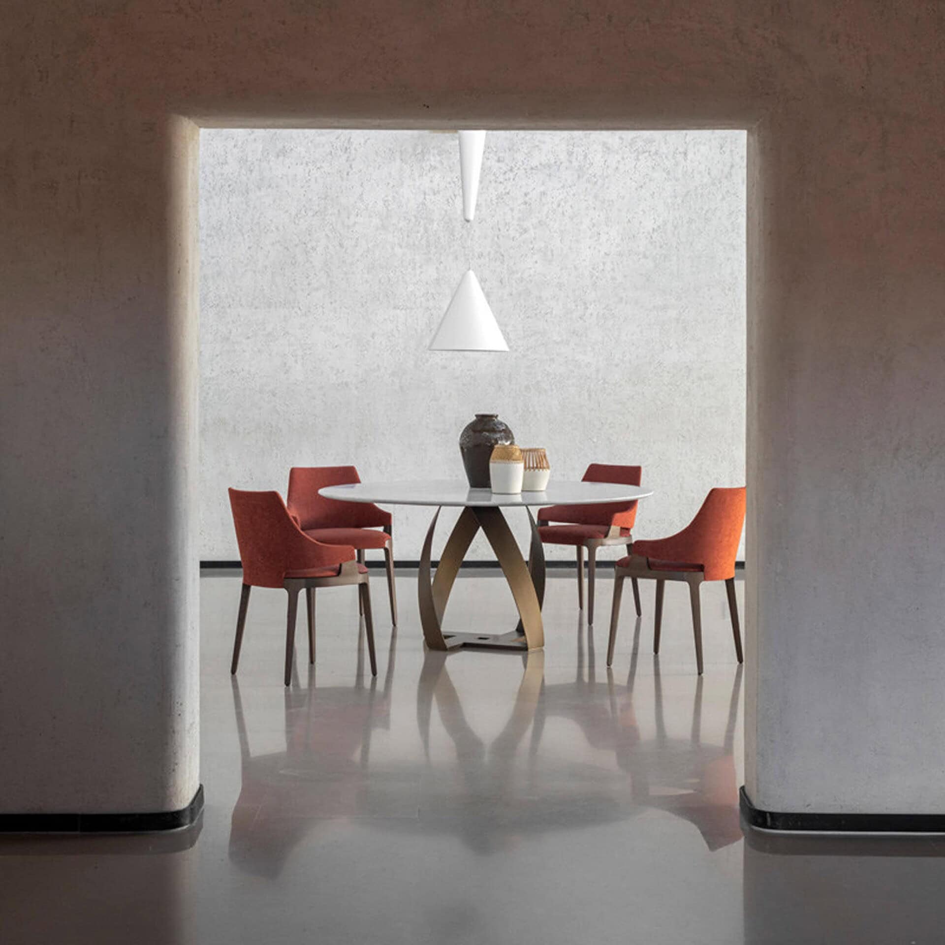 Dining setup with four red Velis chairs surrounding a circular marble table in a minimalist interior.