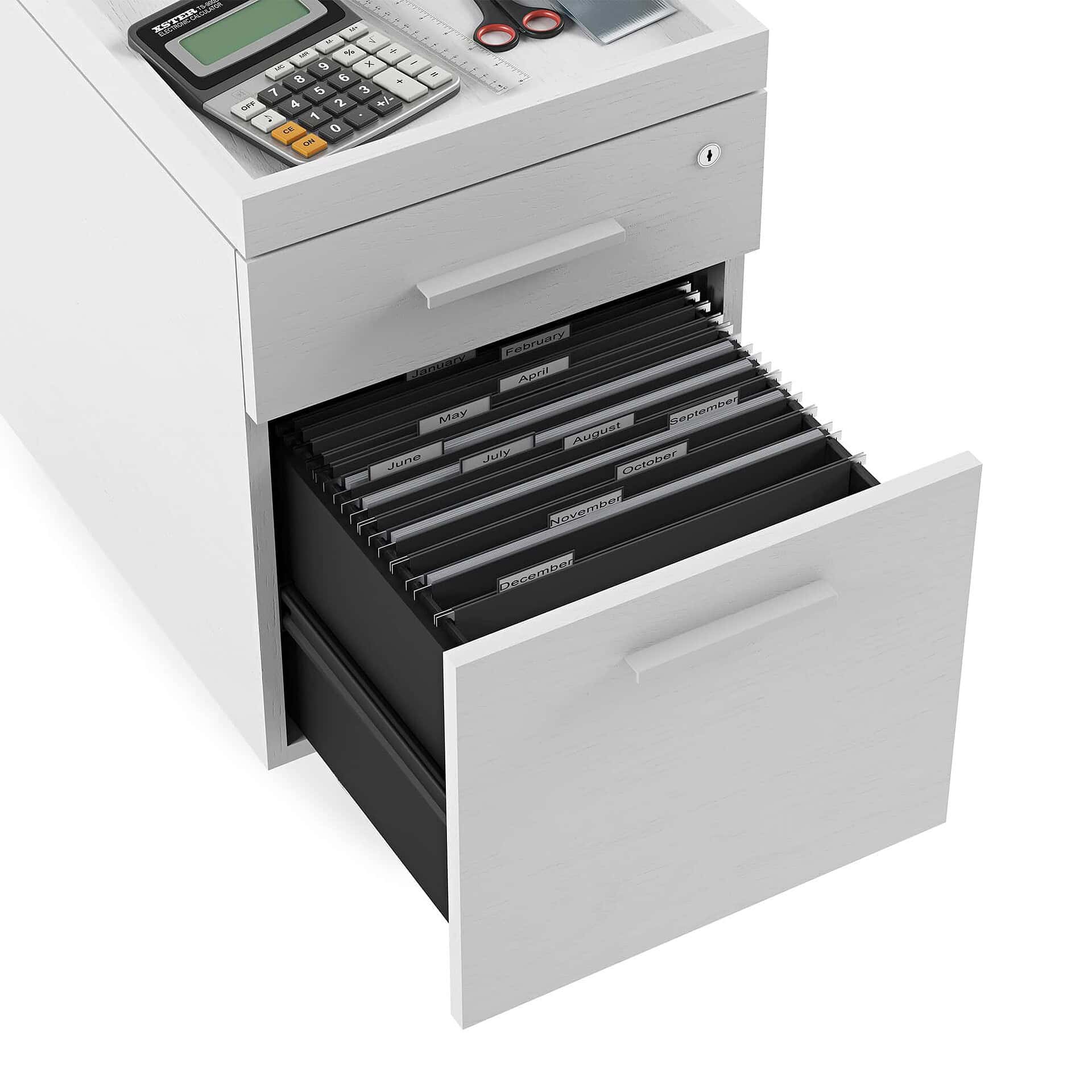 Stacked black and white file folders with monthly labels in a white desk drawer for organized office storage.