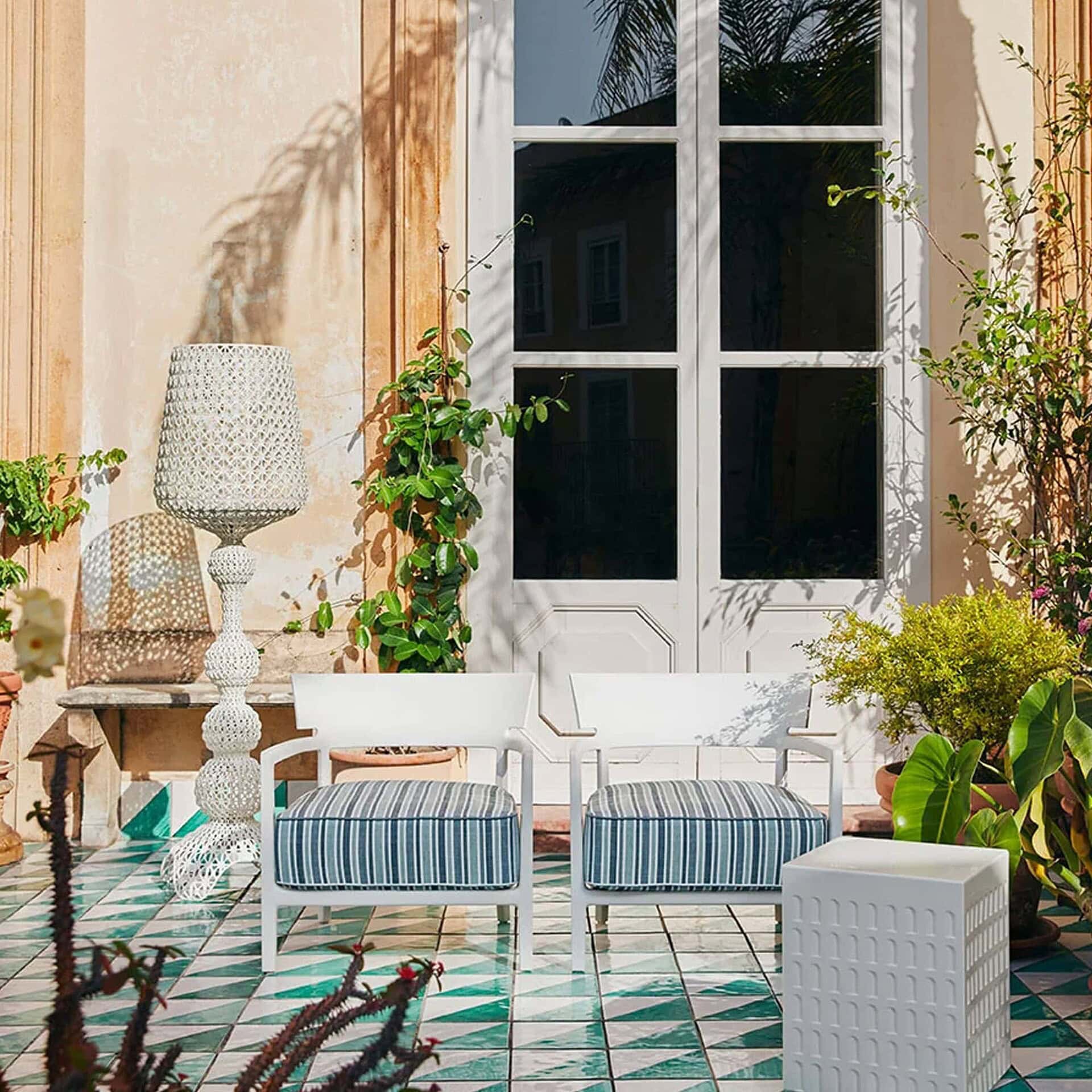 Kabuki Outdoor Floor Lamp in white finish styled in a bright garden patio.