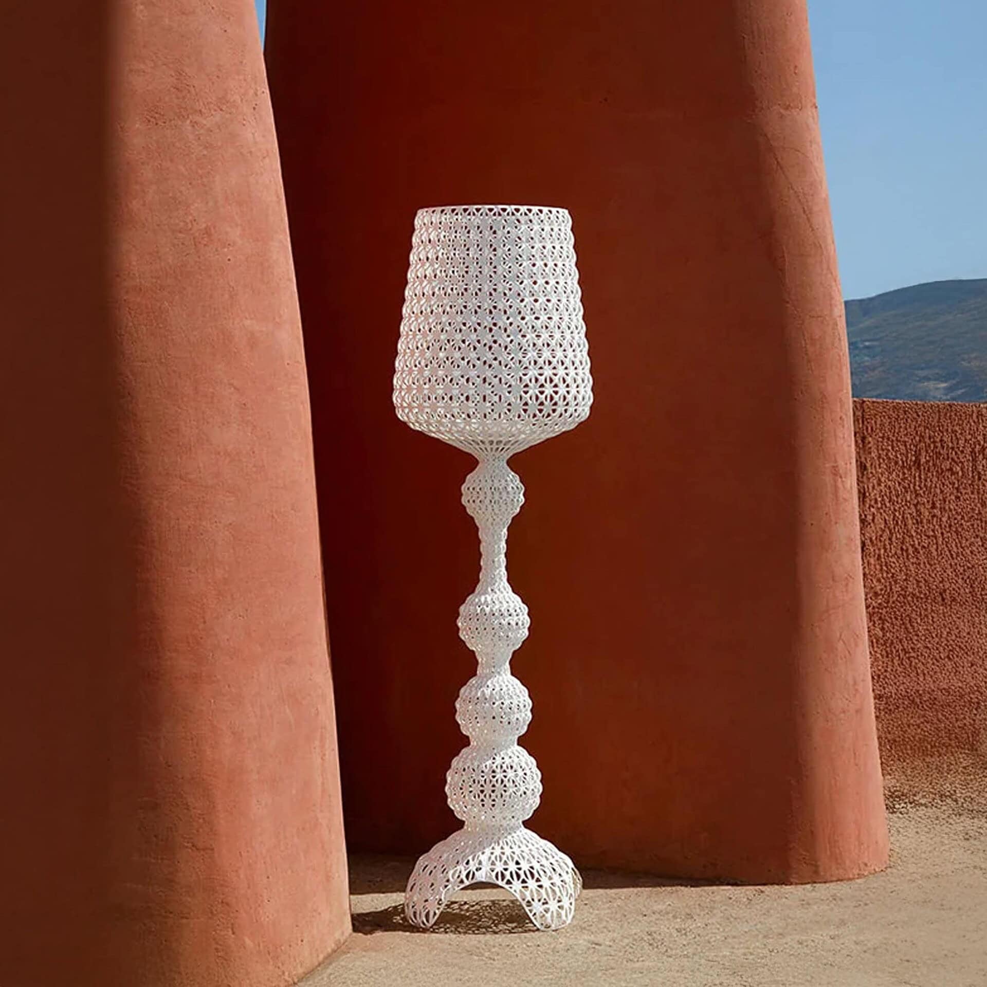Kabuki Outdoor Floor Lamp in white finish placed against terracotta architectural columns.