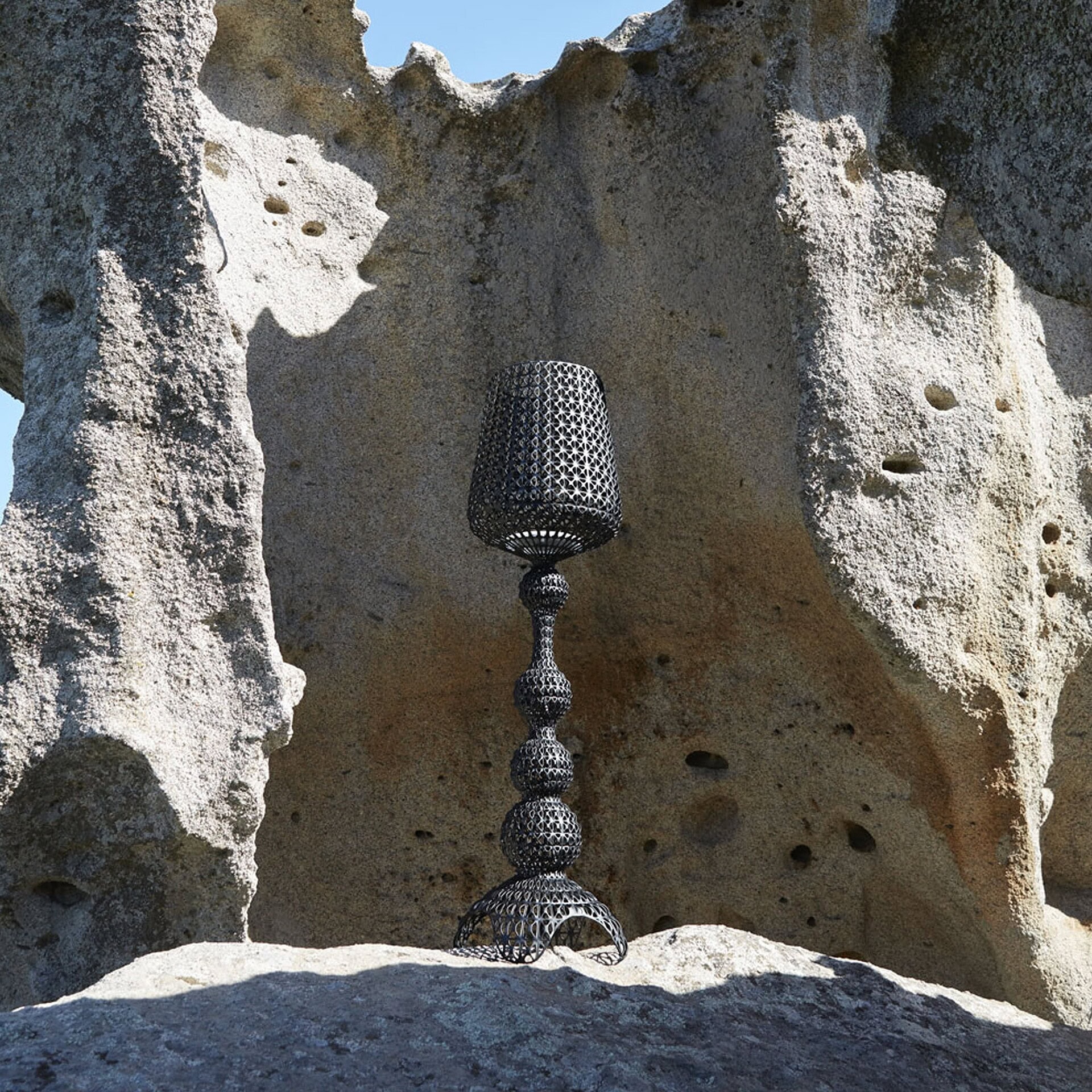 Kabuki Outdoor Floor Lamp in black finish placed in rocky desert terrain.