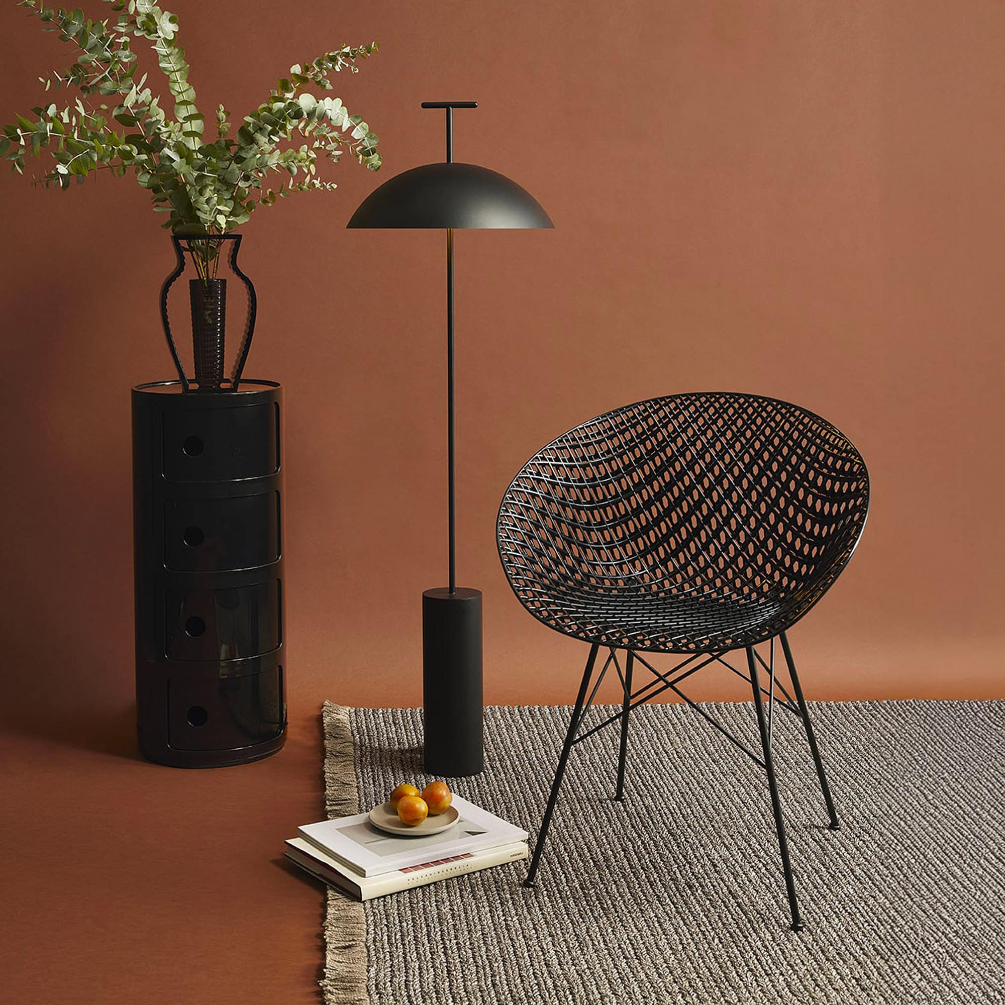 Single black Smatrik Chair styled against a terracotta wall with a floor lamp and decorative vase.