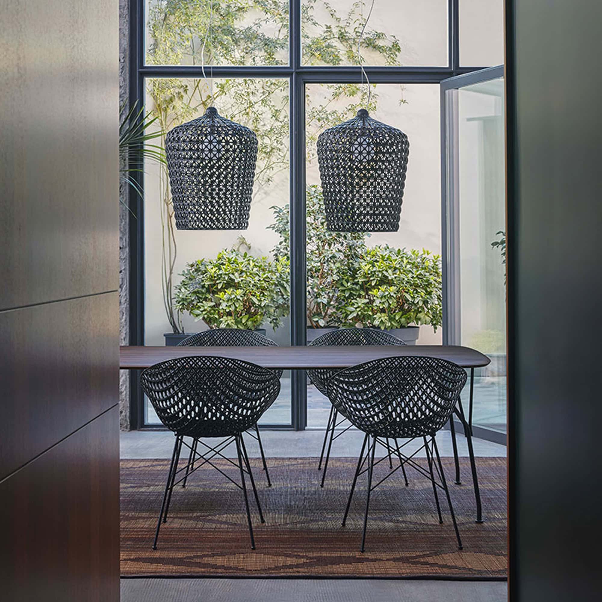 Two black Smatrik Chairs placed at a dining table by large windows in a modern interior.
