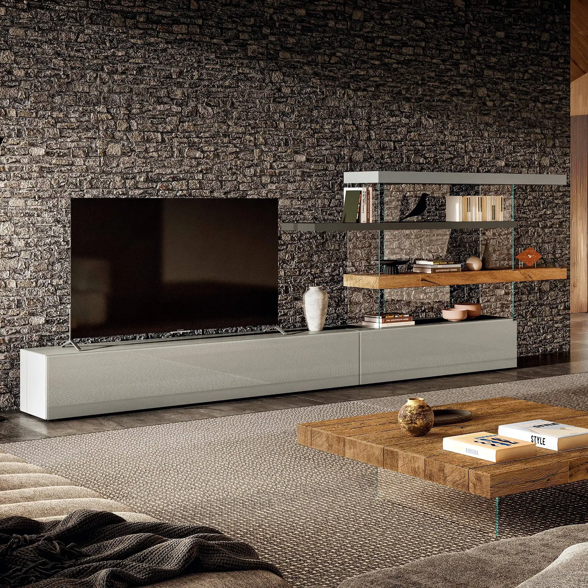 A modern living room with a large TV on a light gray media console against a dark stone wall, flanked by integrated shelving. A rustic wooden coffee table and textured rug are in the foreground.