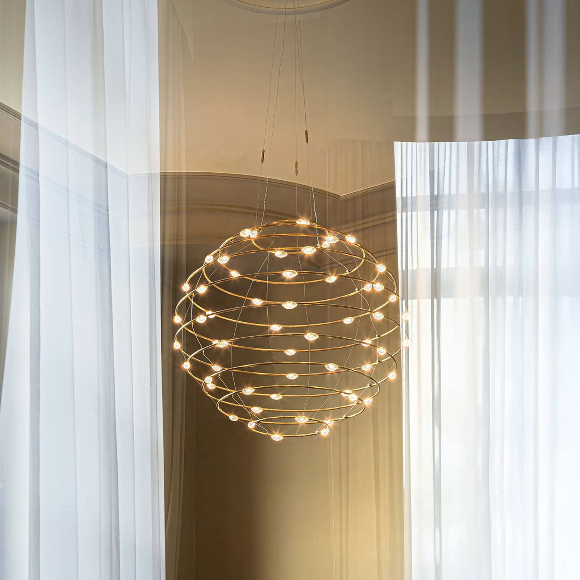 Pendant light fixture with multiple small bulbs arranged in a spherical design, hanging in a well-li.