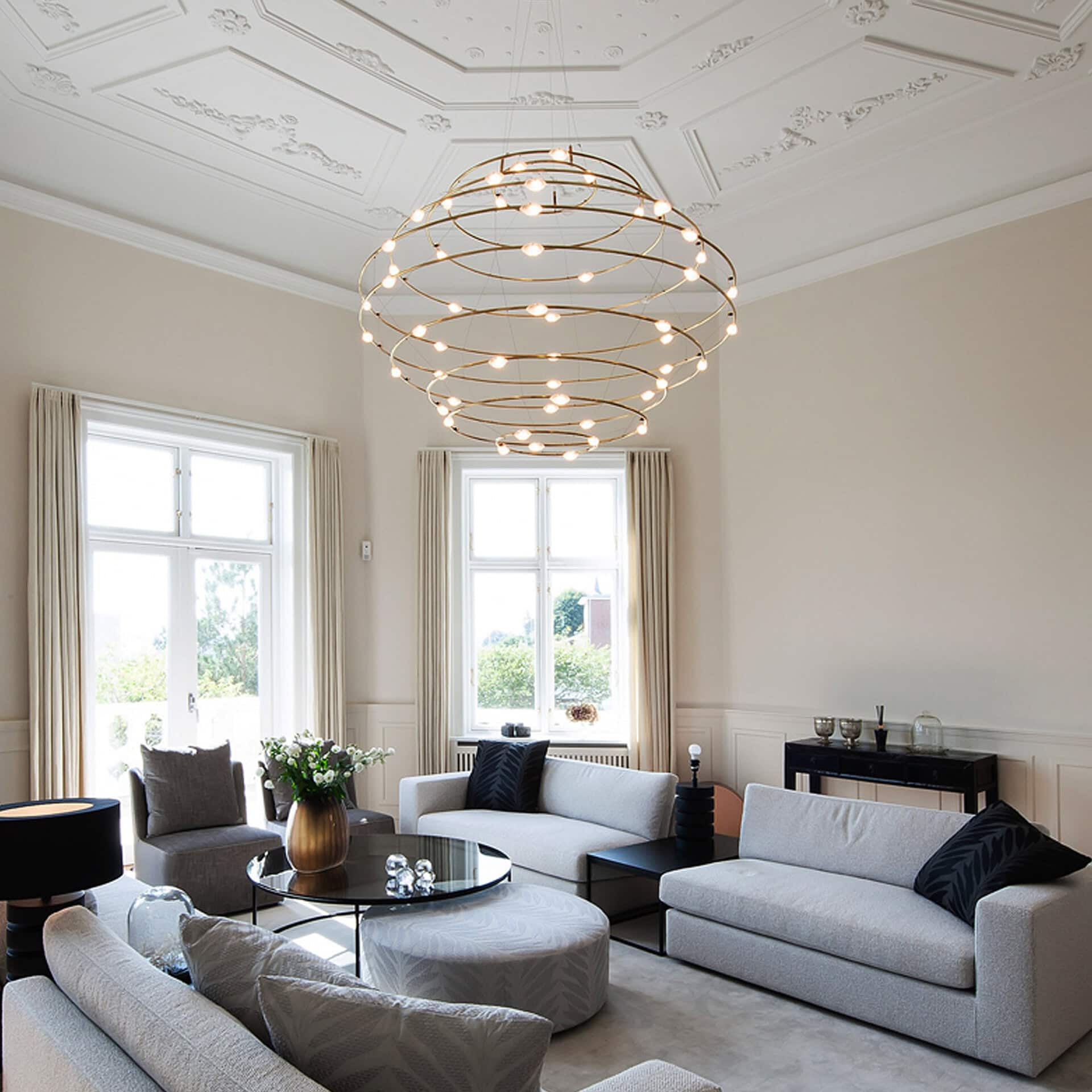 Modern living room featuring a stylish circular chandelier and comfortable sofas. Bright, airy space.