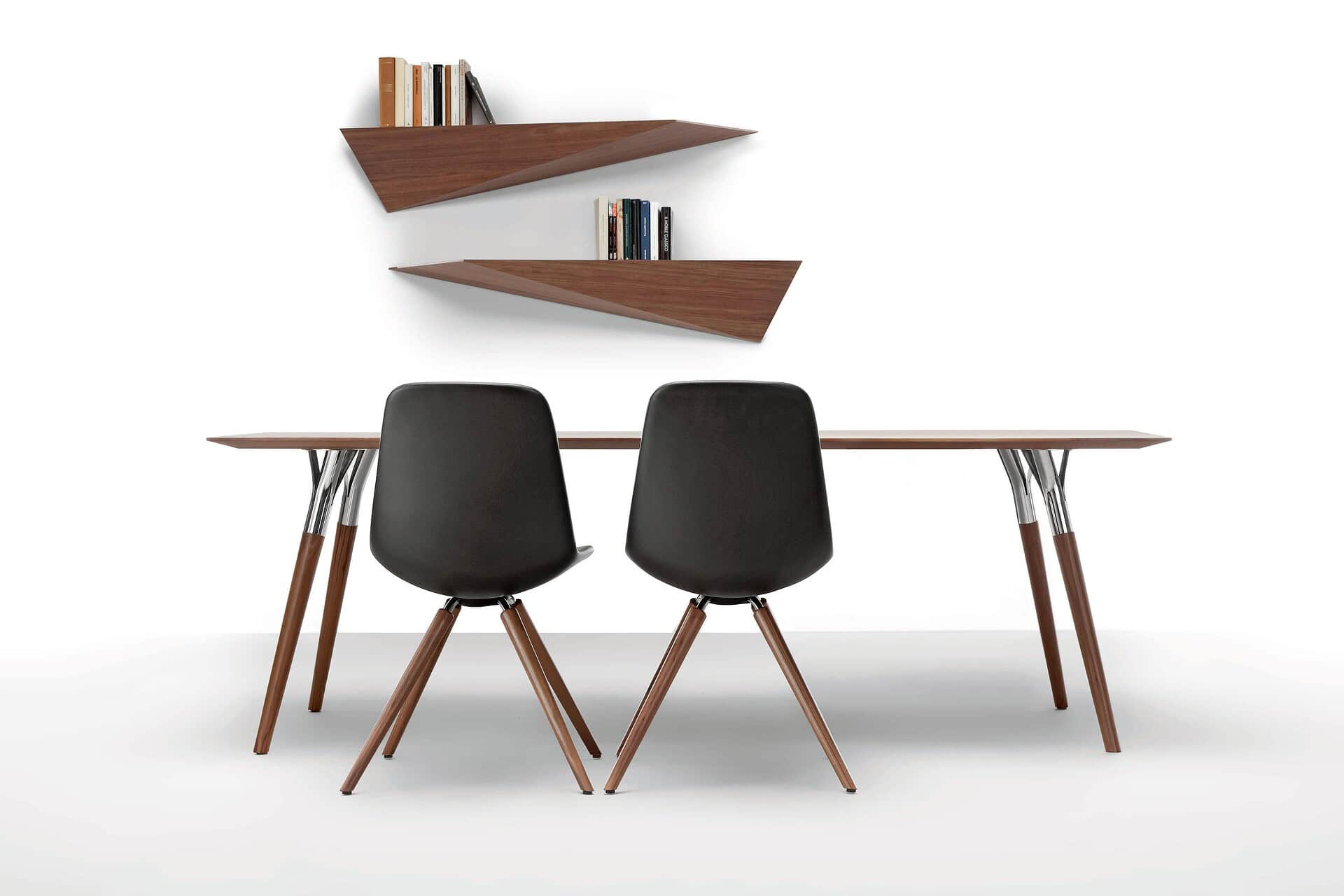 Sleek modern wooden dining table with black chairs and geometric wall shelves.