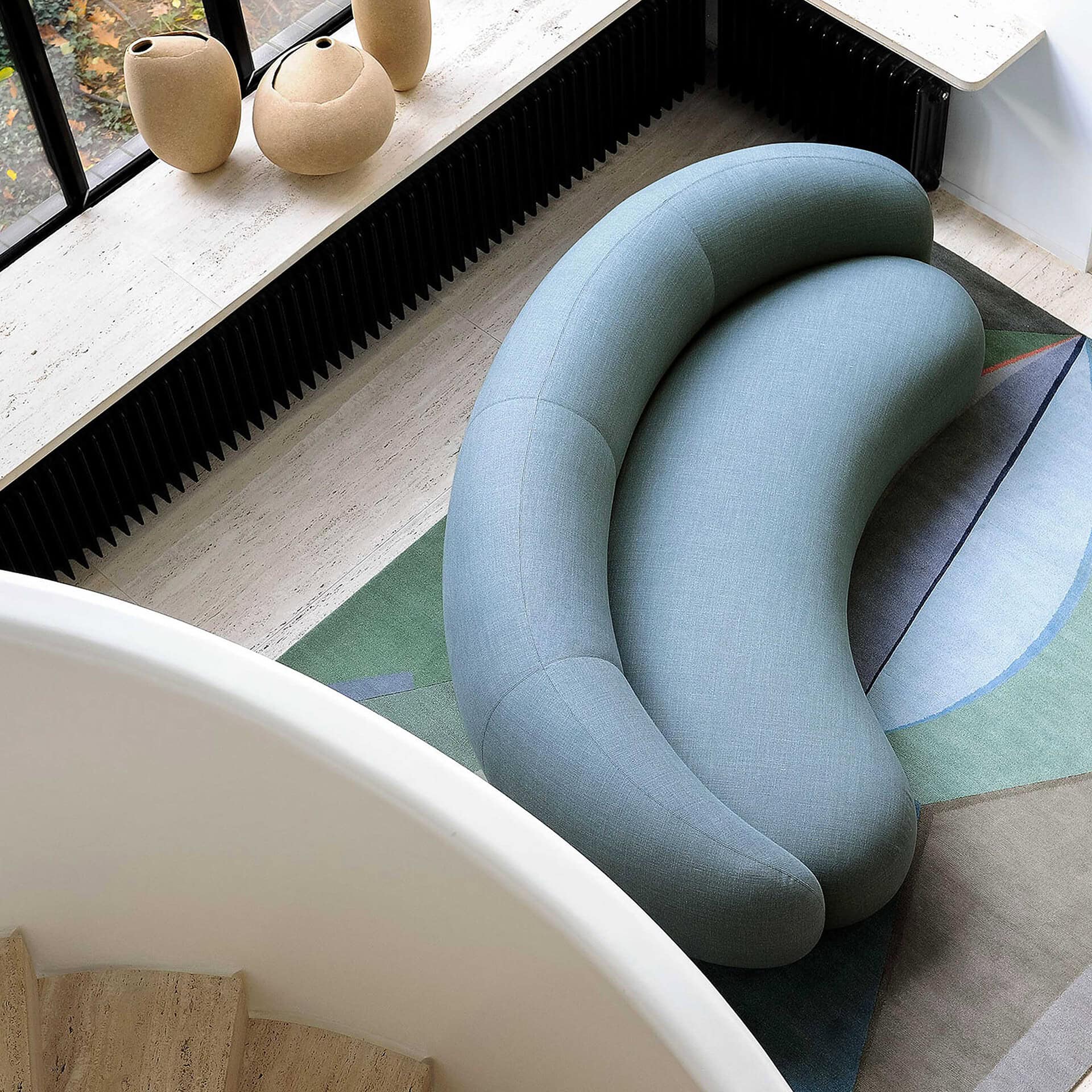 Comfortable modern curved sofa in light blue upholstery at Sklar Furnishings.