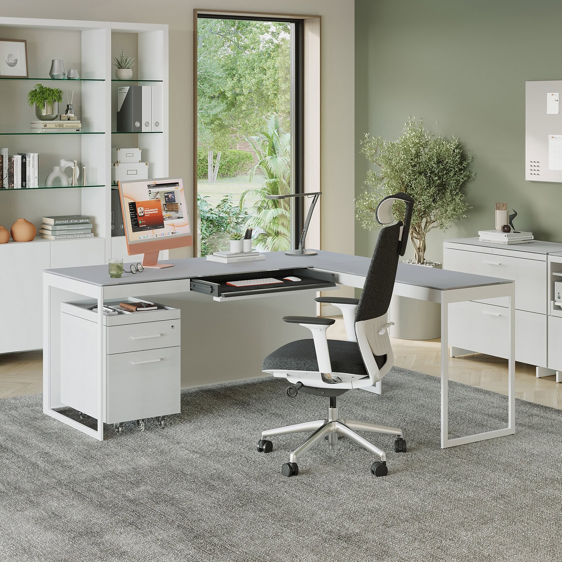 Modern ergonomic office desk setup with white furniture and black accent chair on grey rug.