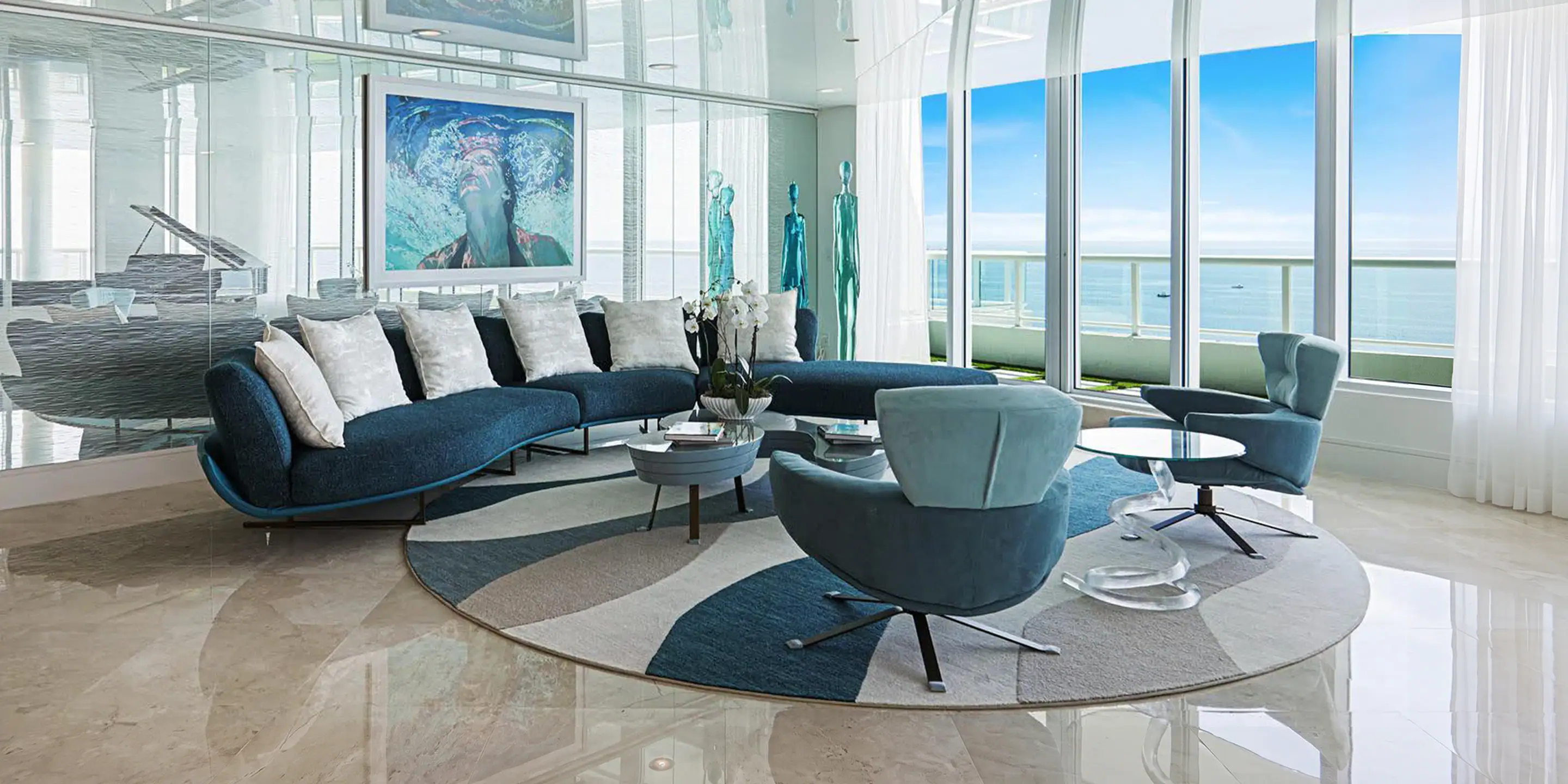 Modern living room with blue sofa and ocean view from large windows.