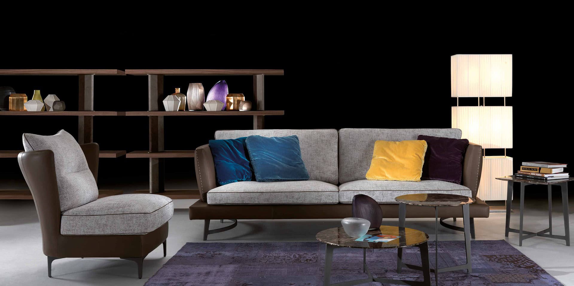 Modern living room with stylish sofa, accent chairs, decorative cushions, and contemporary lighting.