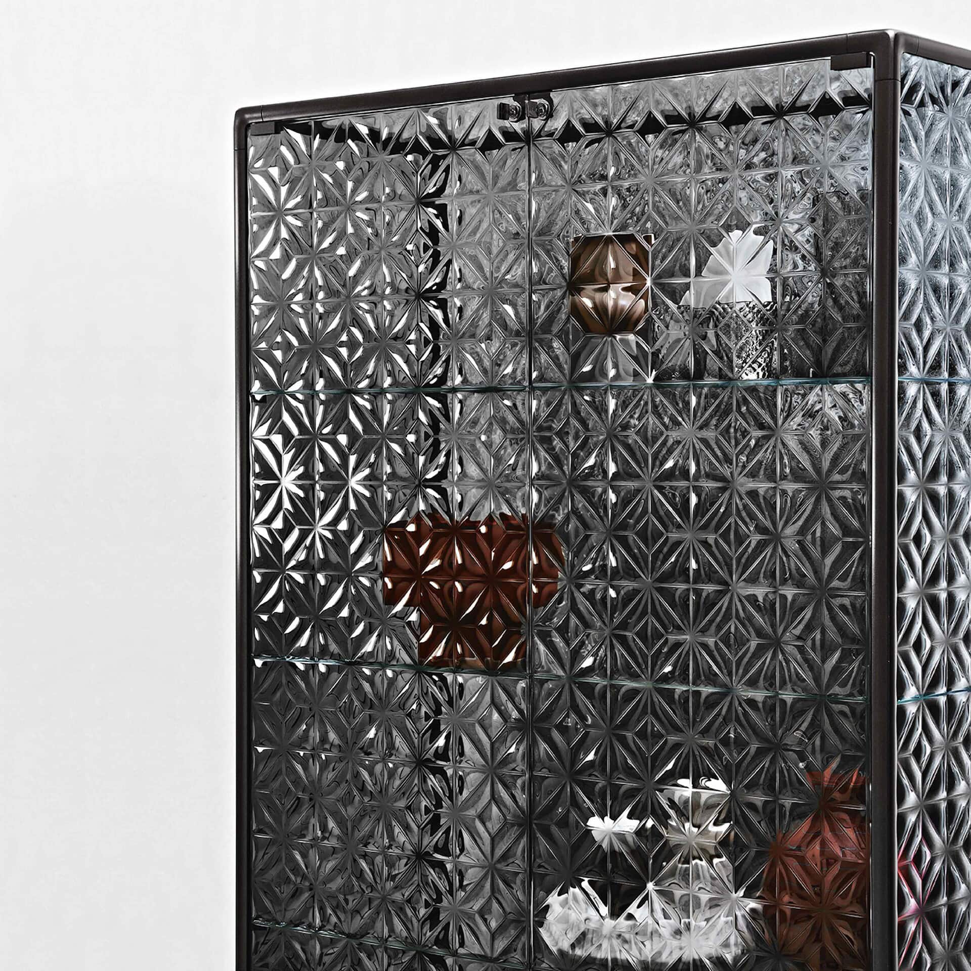 Shawlared glass cabinet with geometric patterns showcasing decorative items and vases.